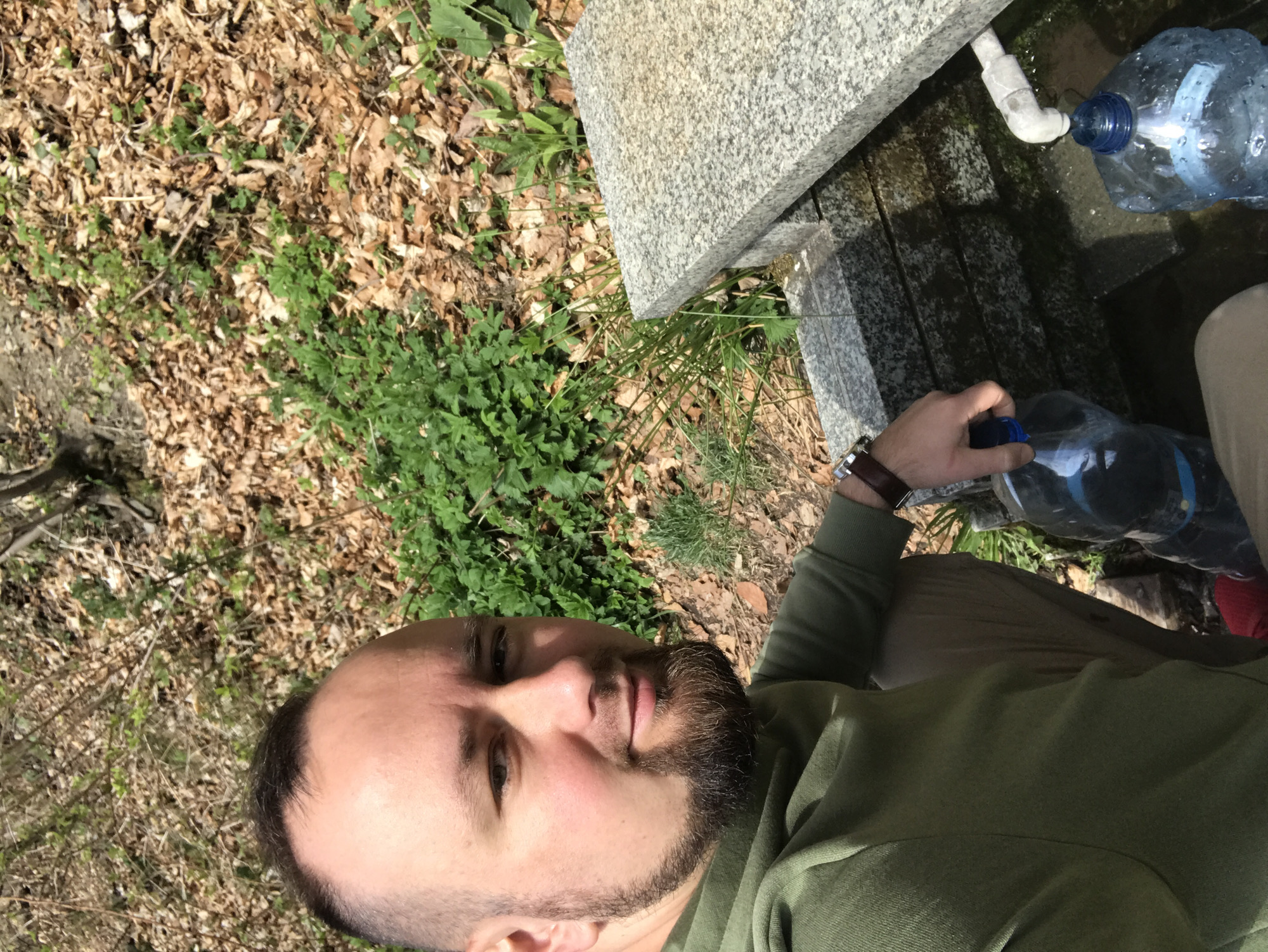 Man fills water bottle at stone fountain in Wisła