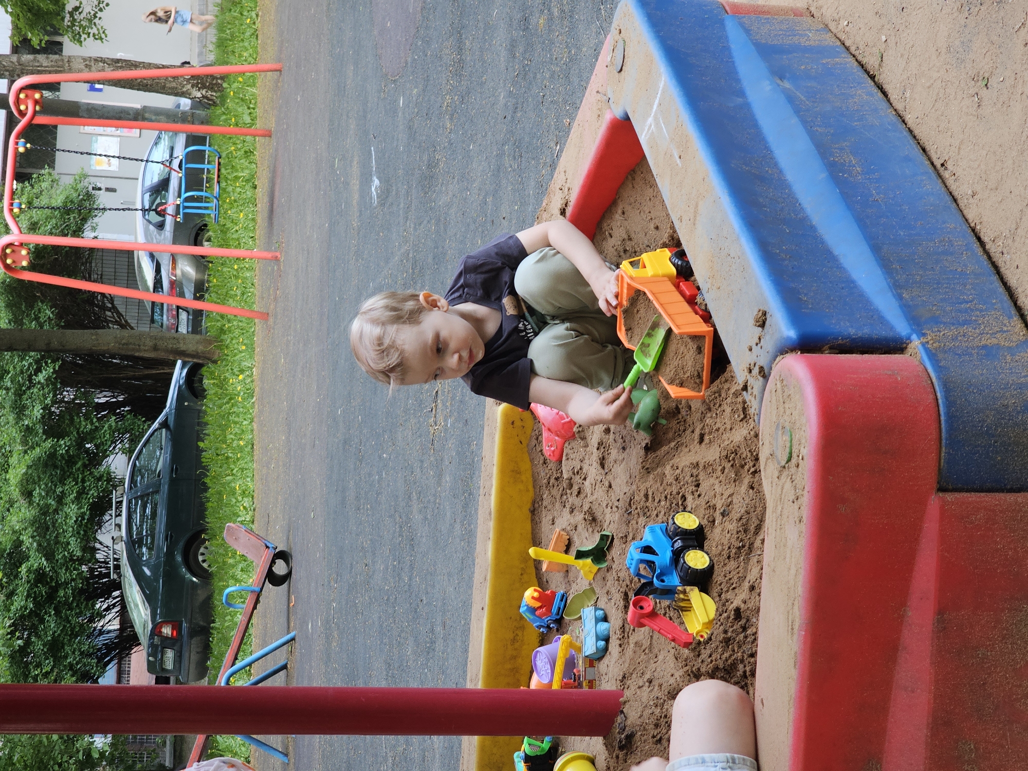 Child plays with toys in colorful sandbox at Khimki playground