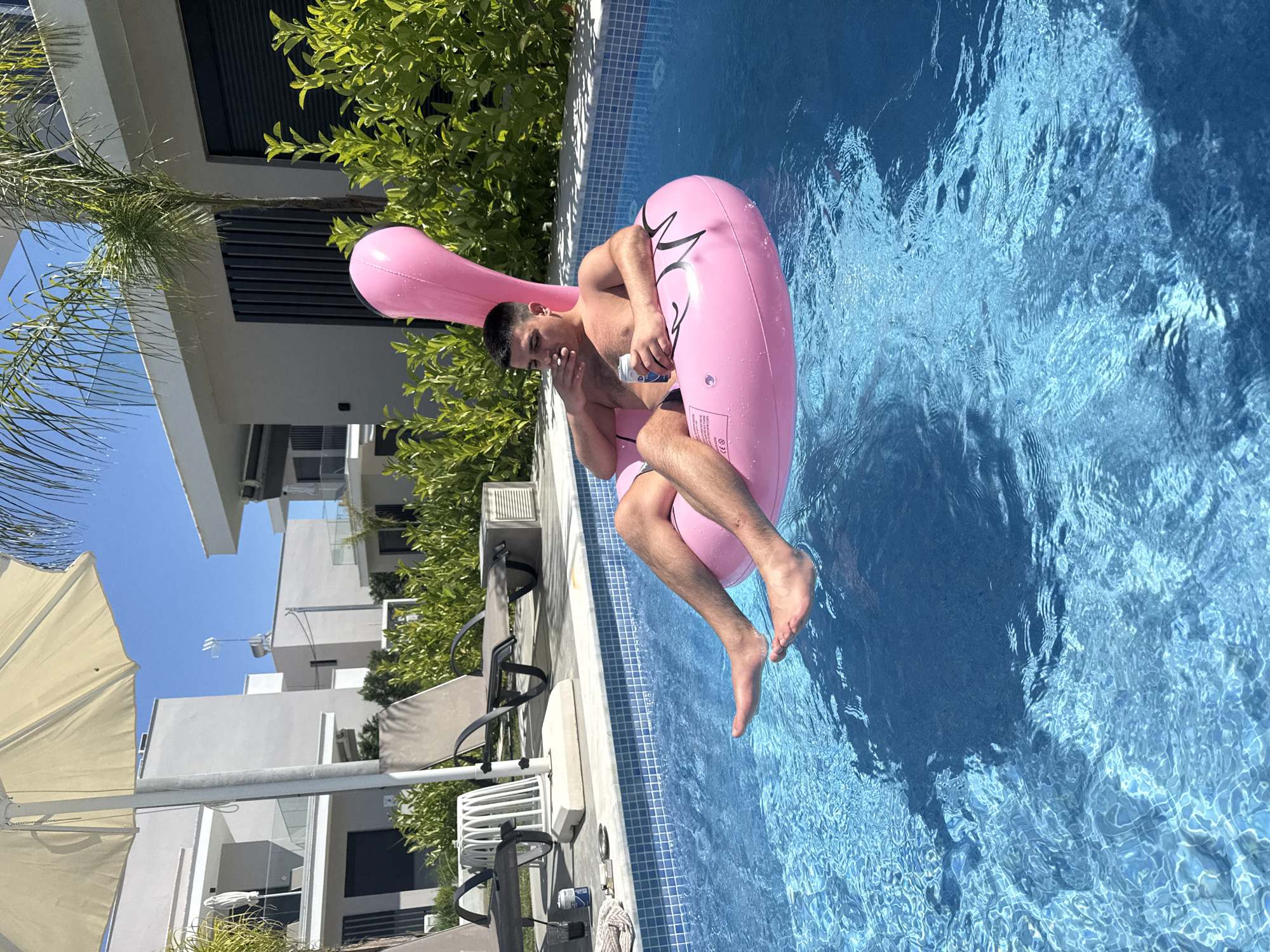 Man enjoys pool time on flamingo float at Greek beach