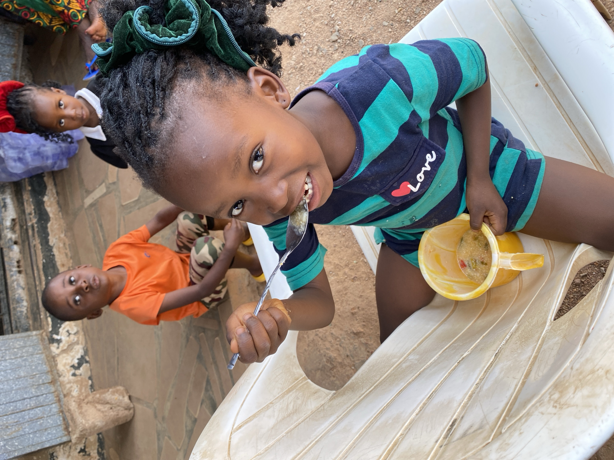 Children share mealtime on porch in Kuru Karama Nigeria