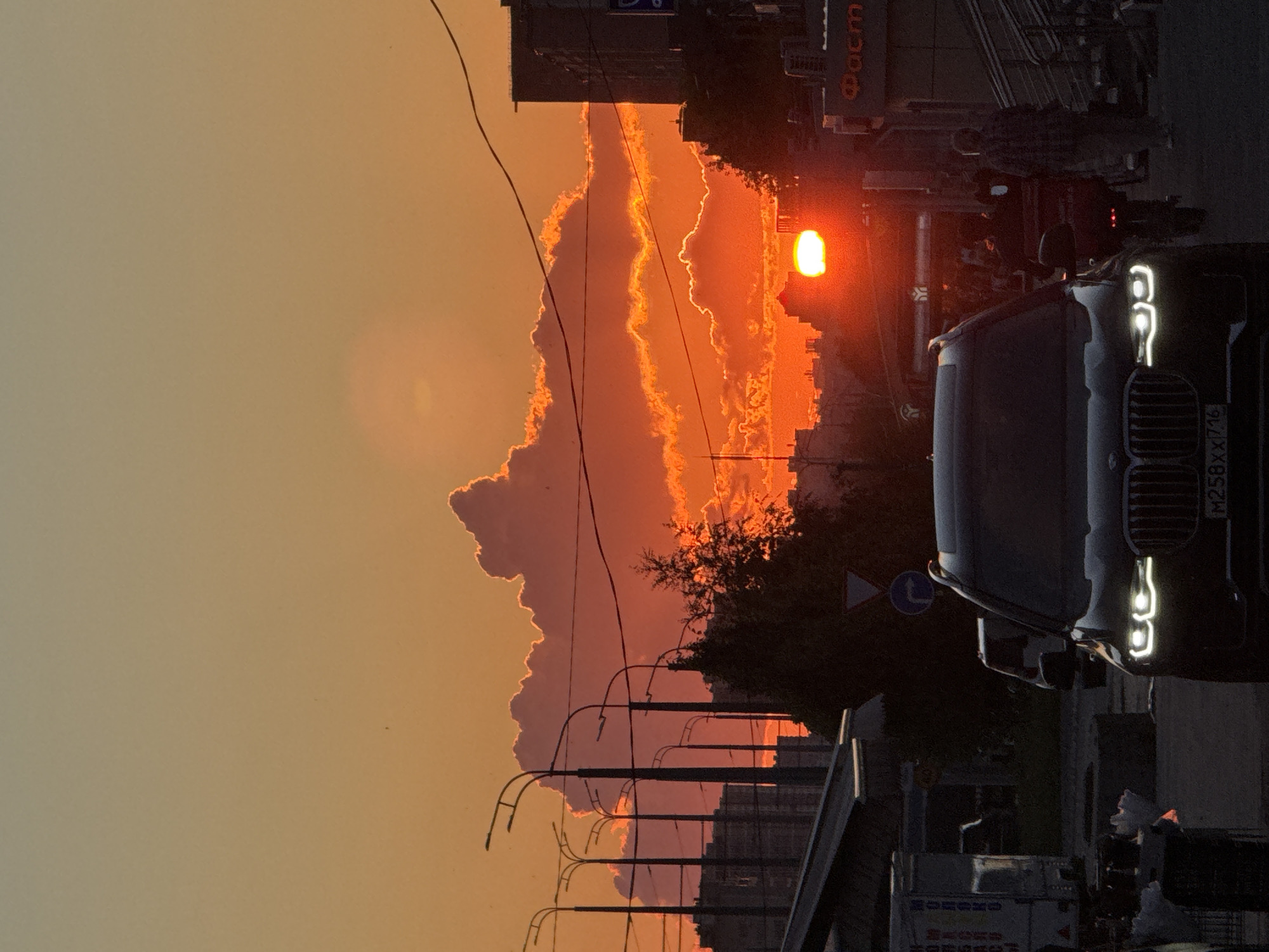 Kazan street at golden hour, dark SUV under a fiery sky
