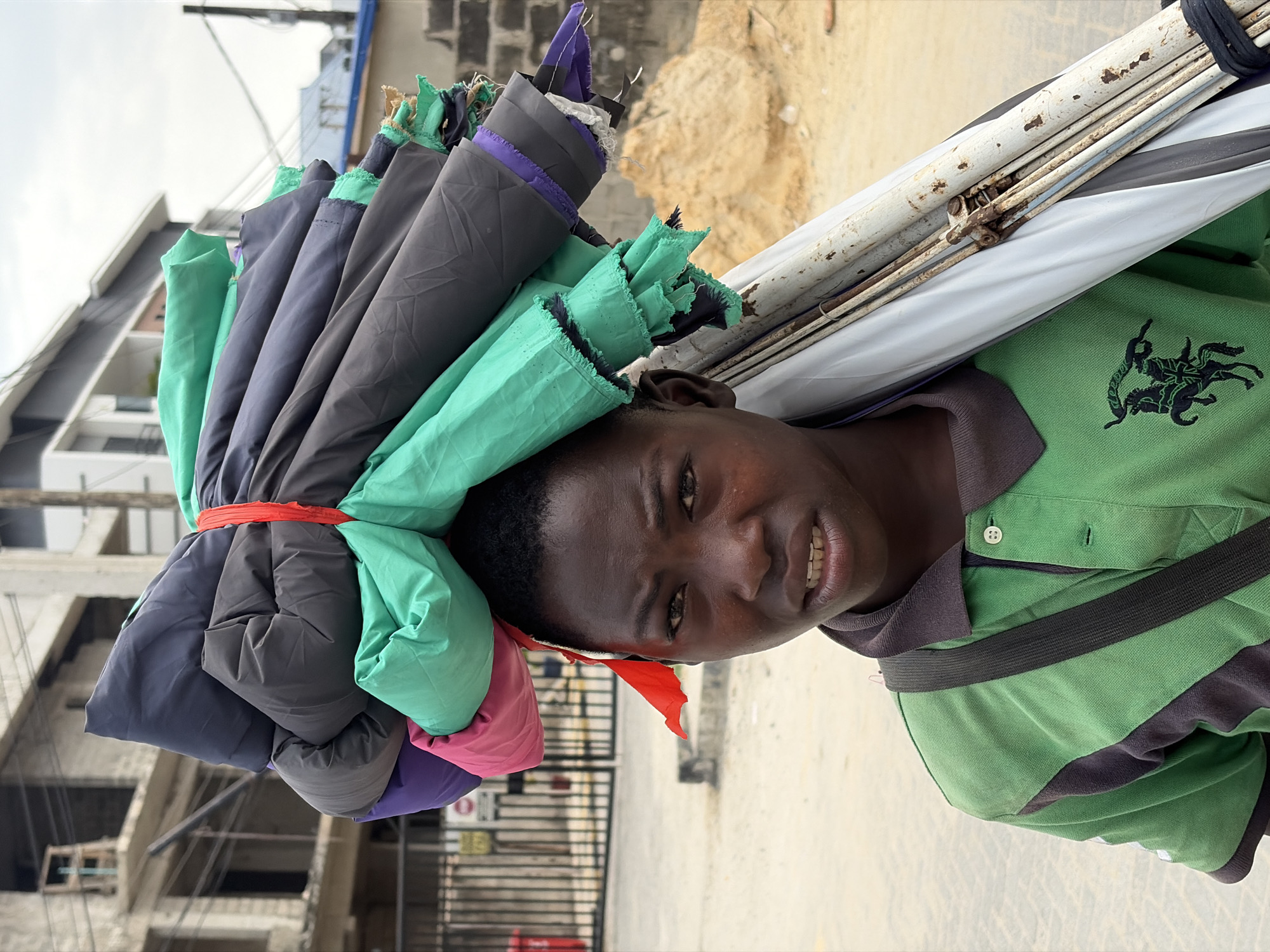Umbrella vendor carries colorful stack through Igboefon streets