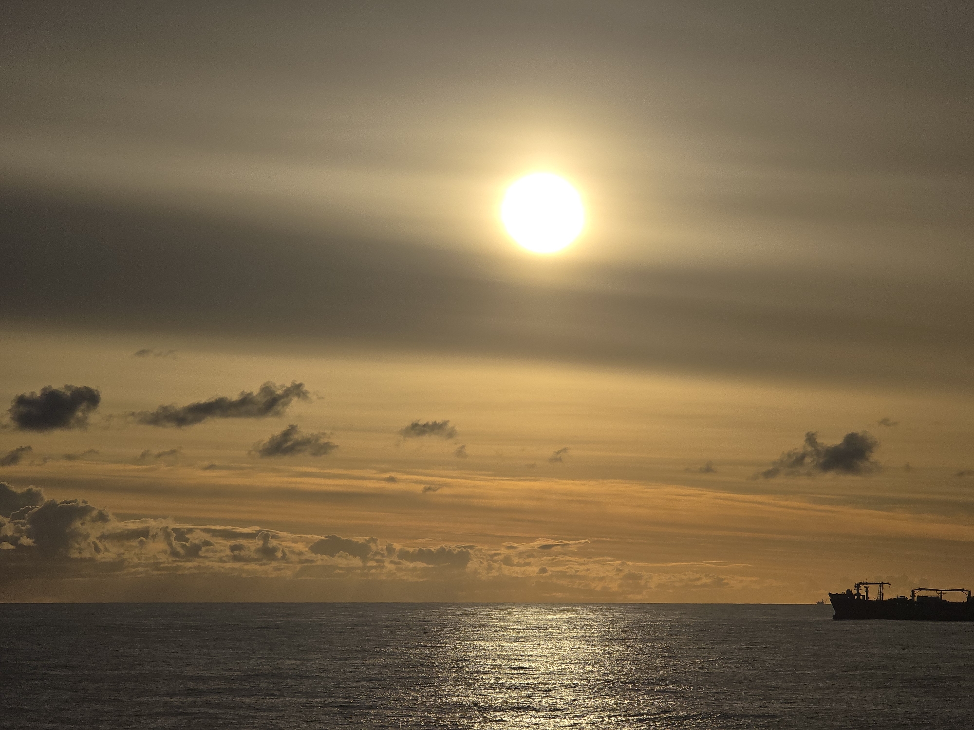 Ocean sunset observed with ship on horizon