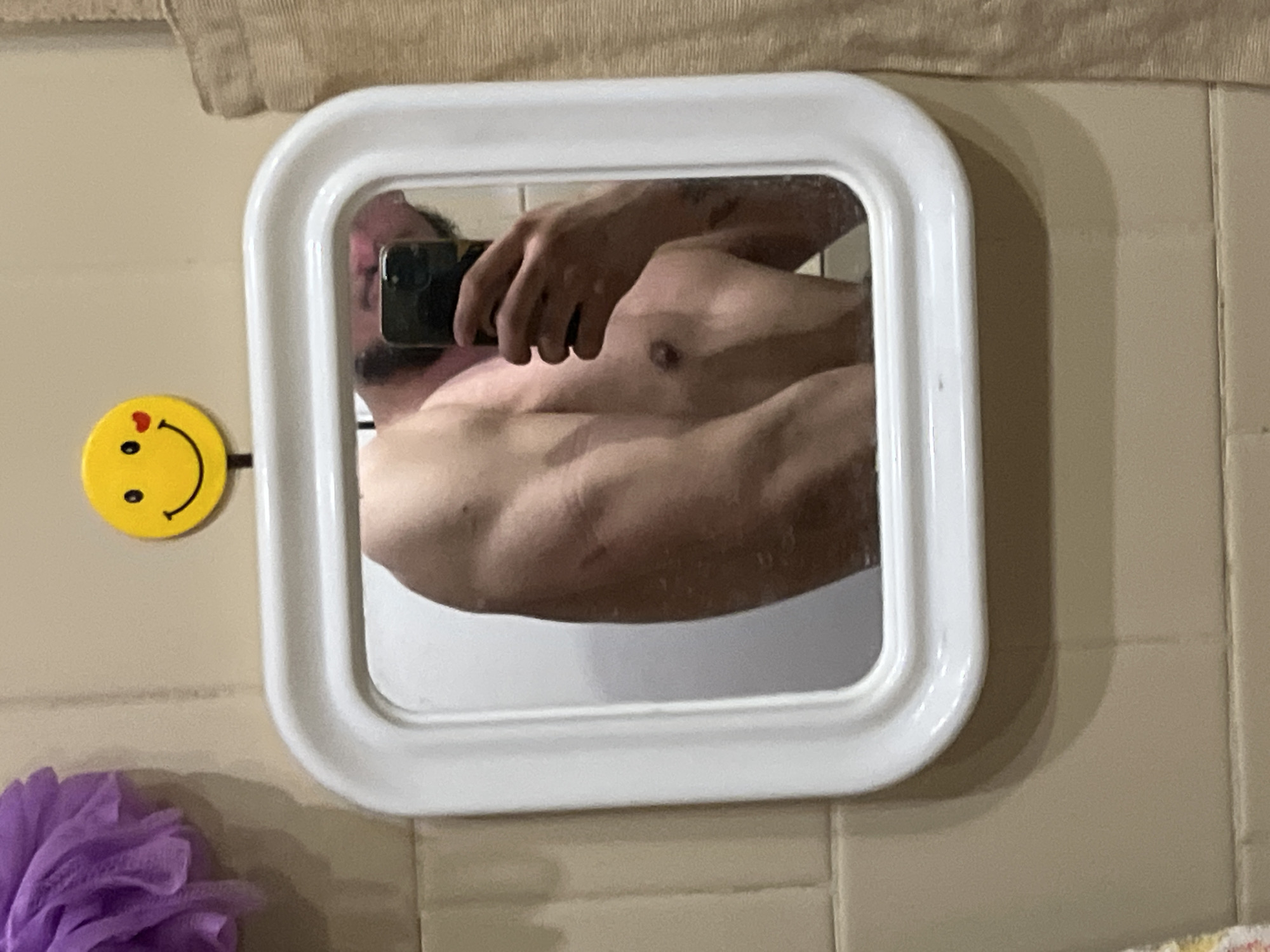 Person takes bathroom mirror selfie in white-framed mirror