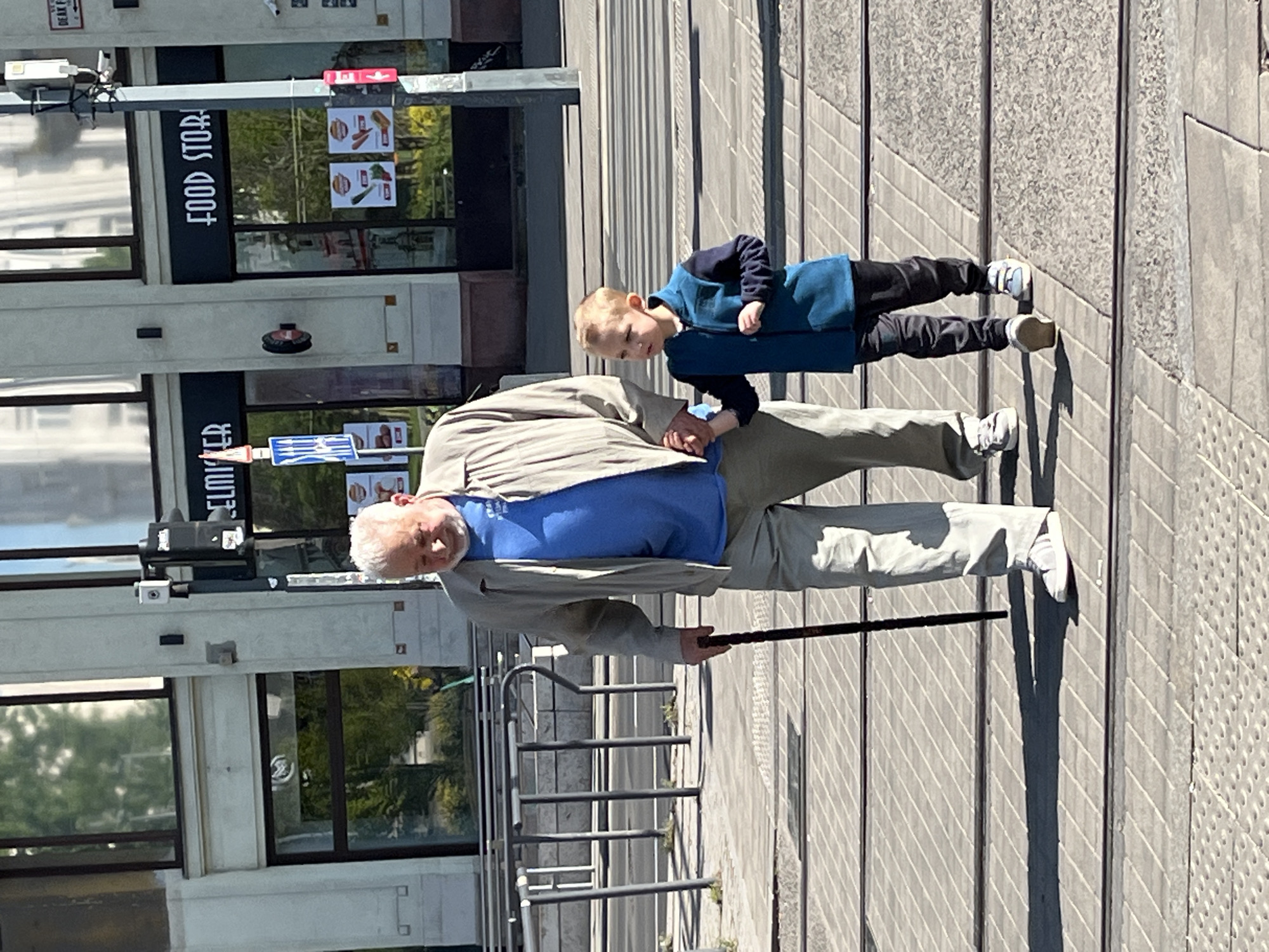 Elderly man, young boy share moment outside Budapest food store