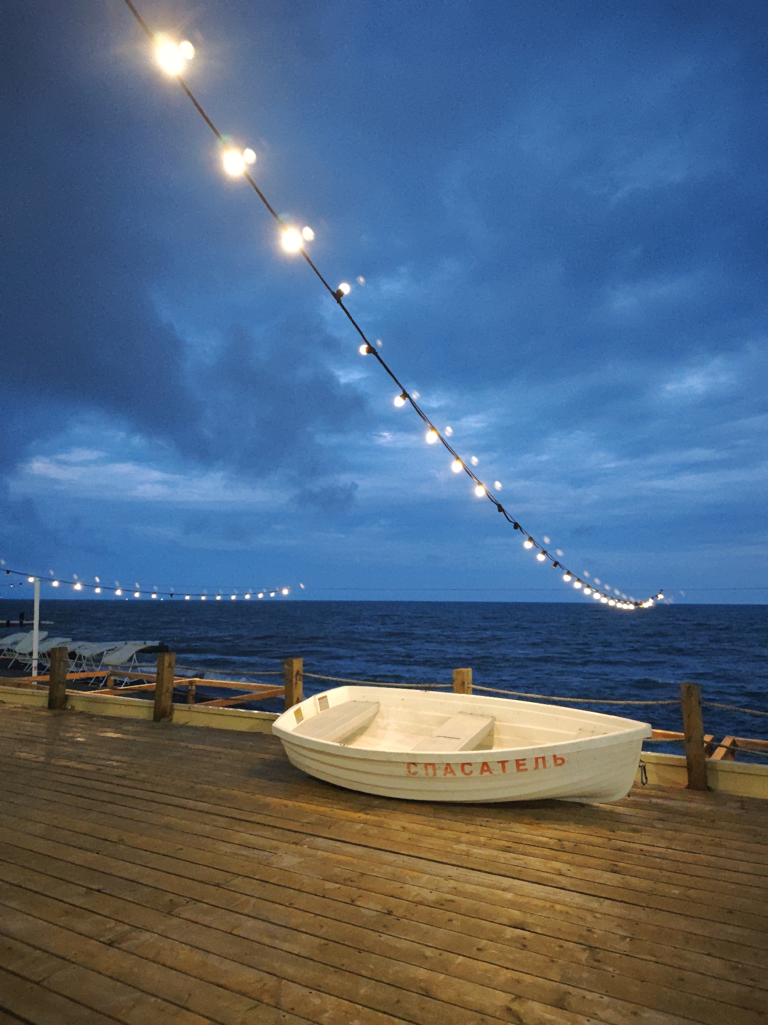 Tourist documents evening stroll along Sochi's illuminated waterfront pier