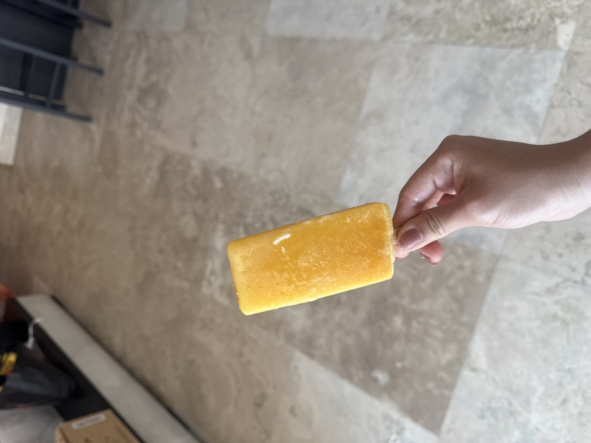 Person enjoys yellow popsicle indoors in Acapulco