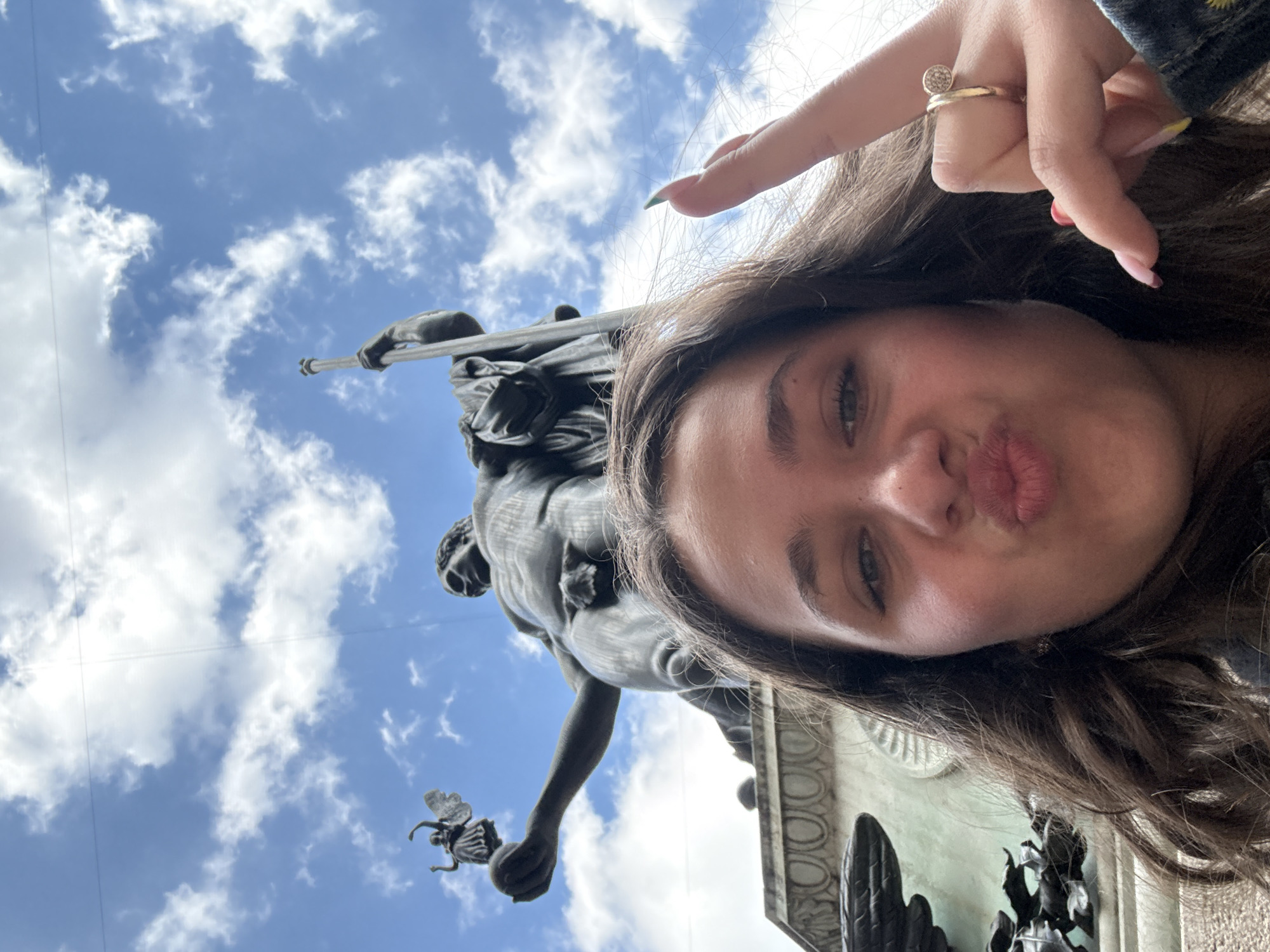 Tourists gather at Milan historic courtyard, pose with bronze statue