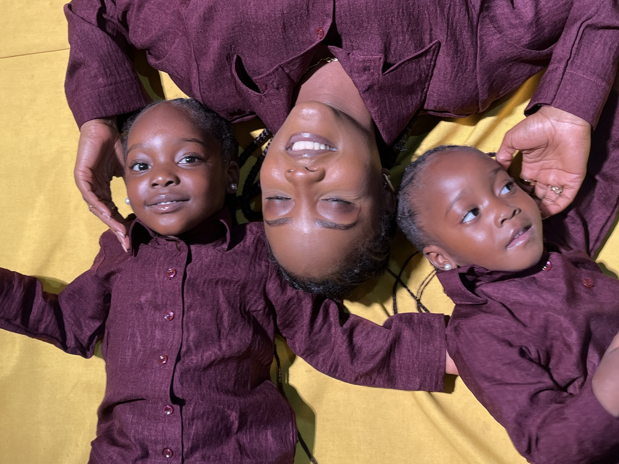 Matching maroon shirts on a mustard-yellow surface in Jos