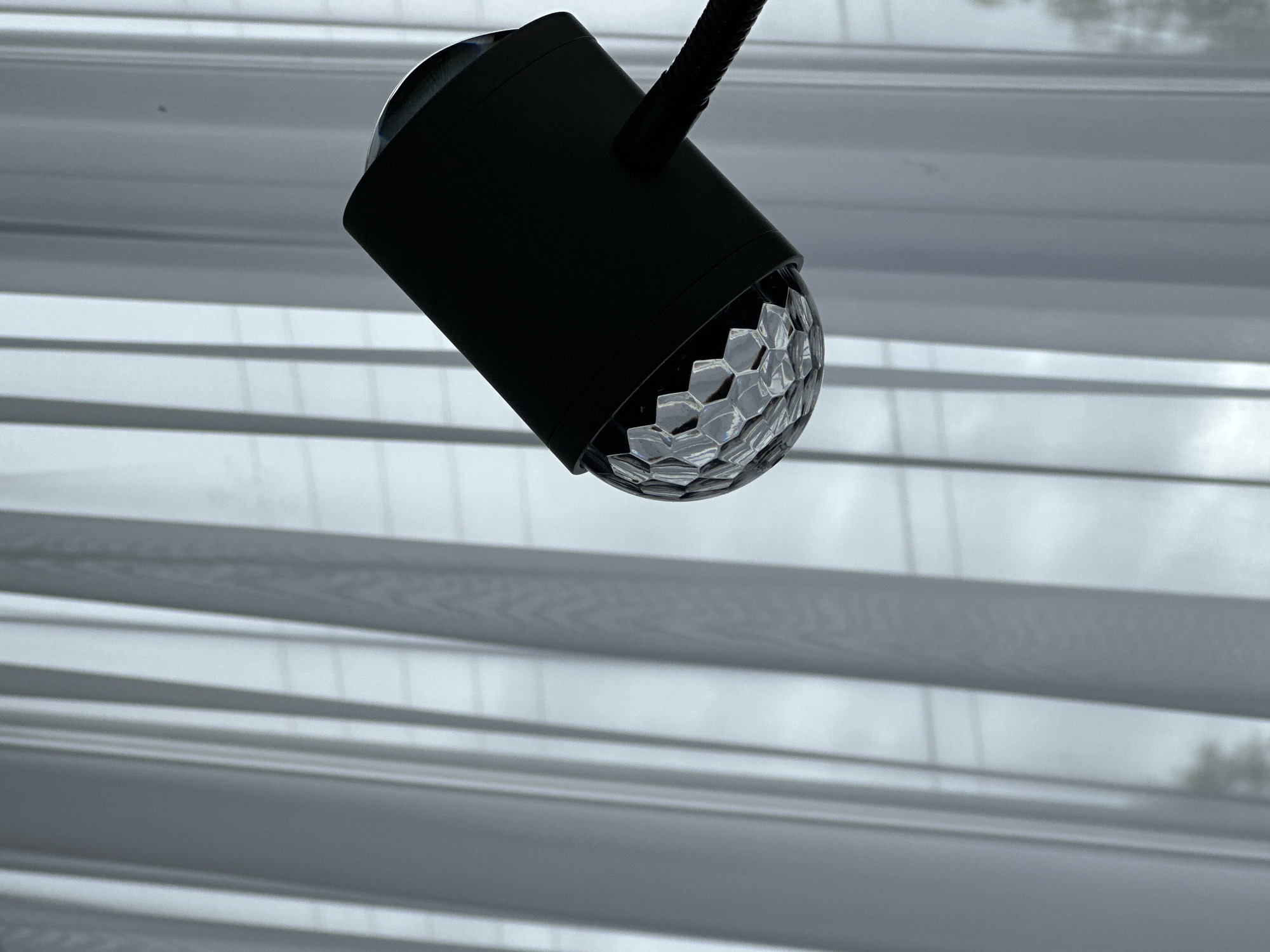 Black desk lamp with faceted dome bulb observed near blinds