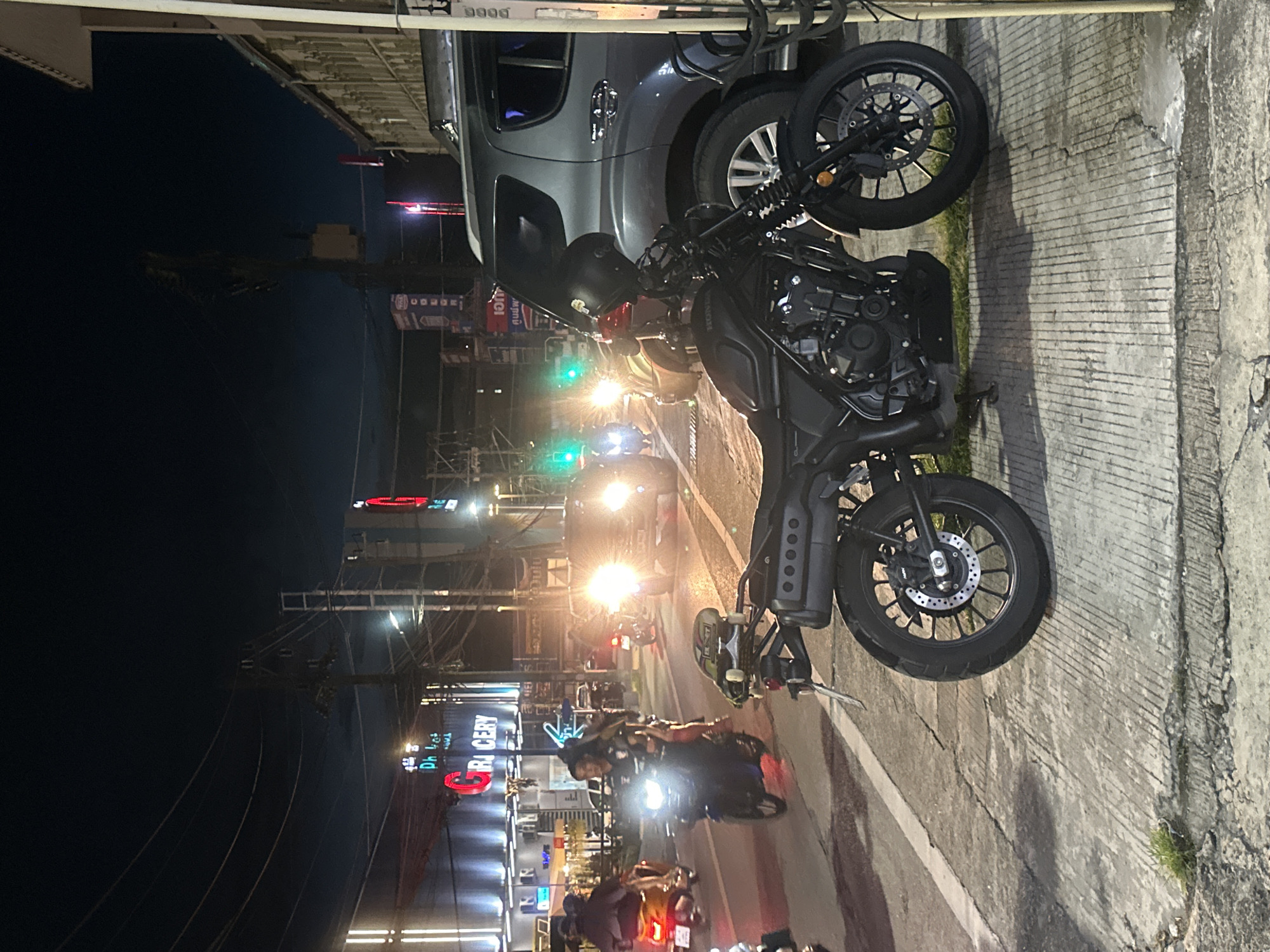 Motorcycle and skateboard parked on a Wichit sidewalk at night