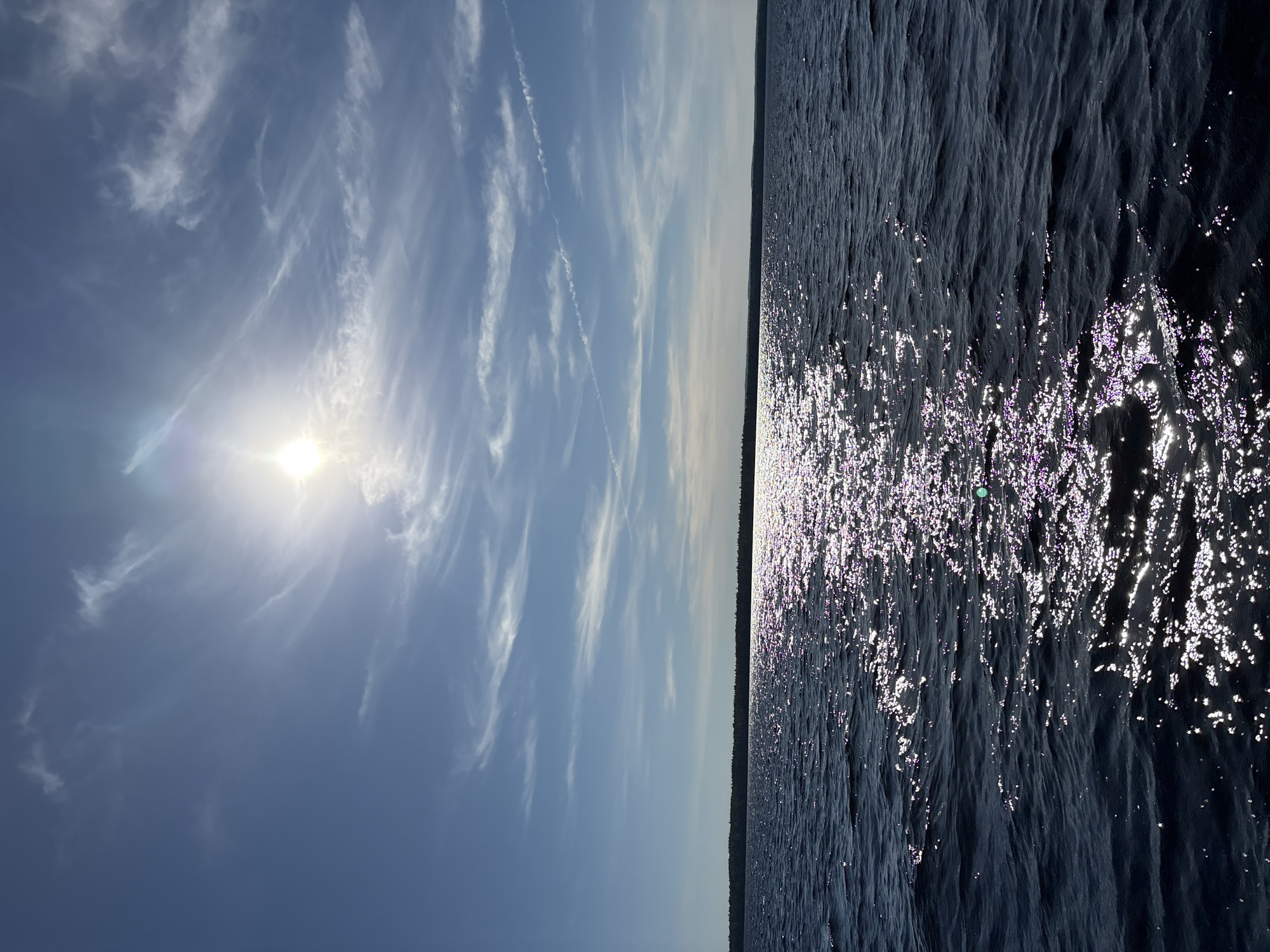 Sunlit dark blue water under a hazy summer sky in Karelia