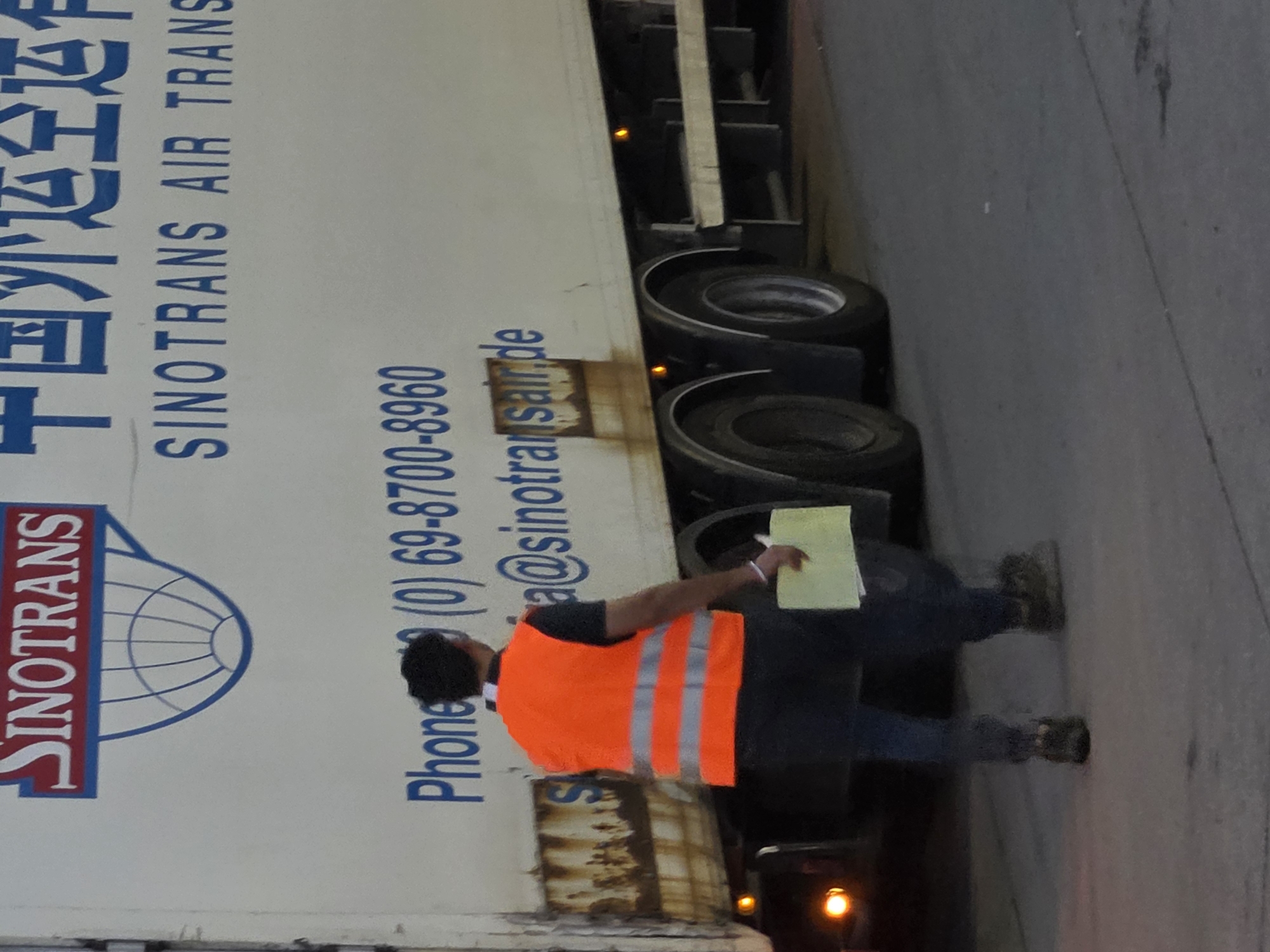 Frankfurt truck yard, freight workers and air cargo trailers in motion