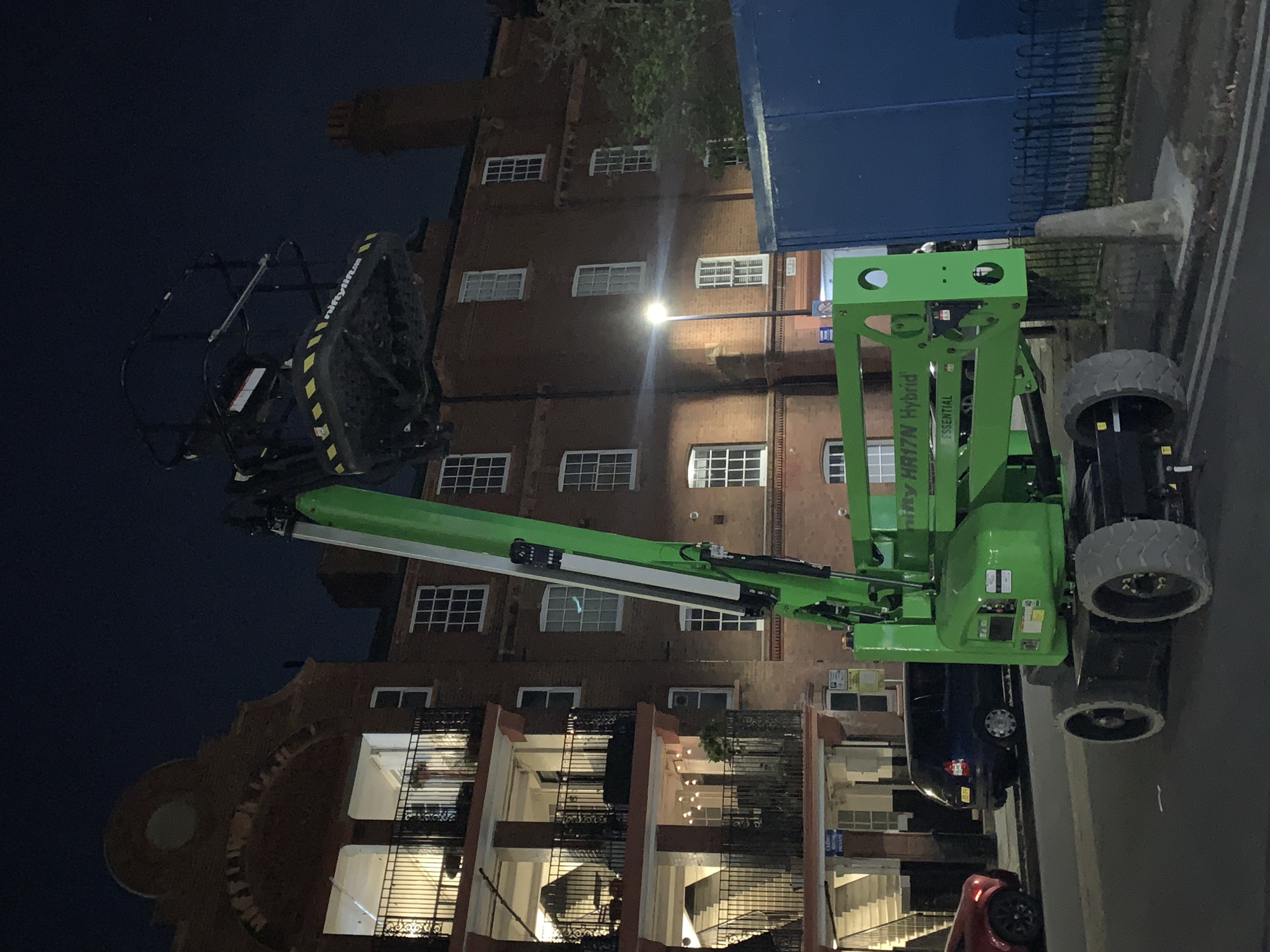 Green aerial work platform spotted in London nighttime scene