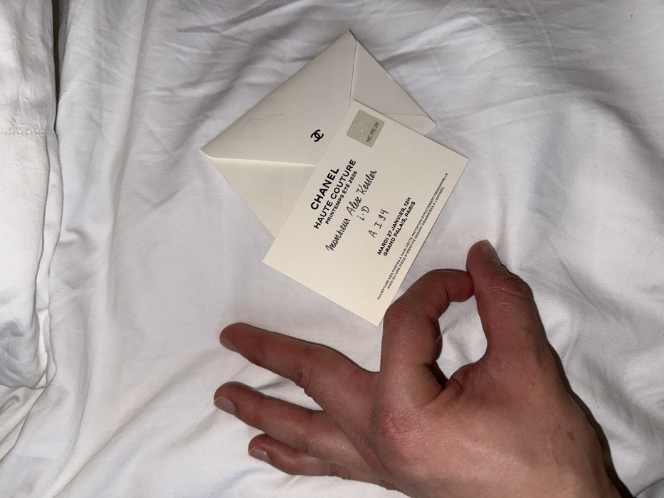 Person makes OK hand gesture on white fabric in Paris