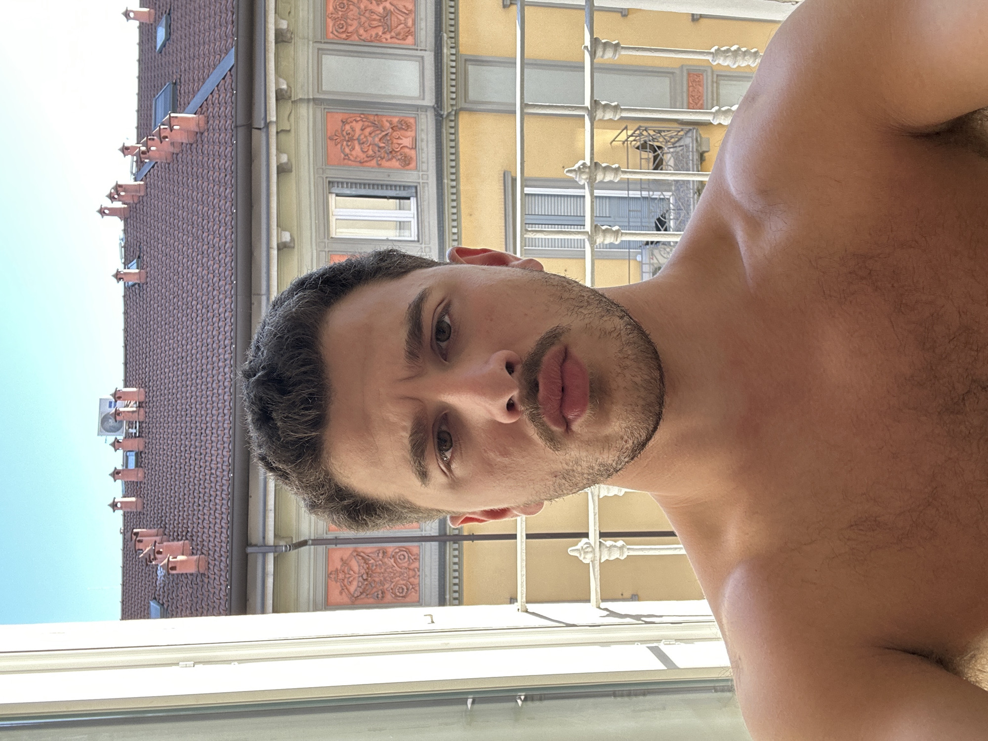 Man takes shirtless selfie by window in Milan
