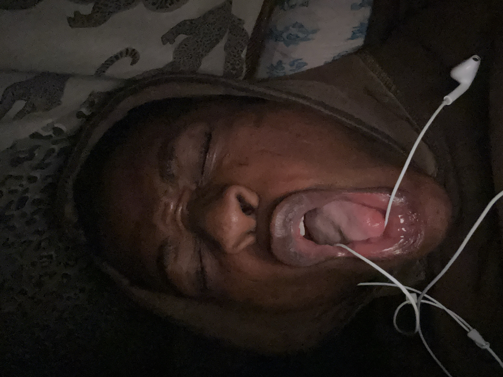Person uses dental device in bed with earbuds