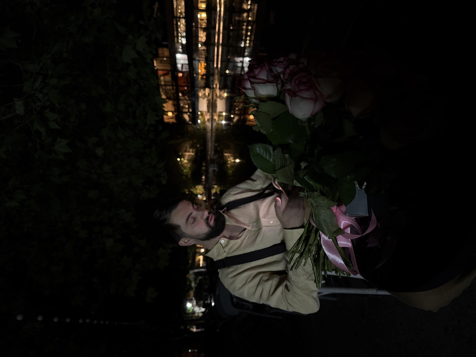 Man holds rose bouquet outdoors in Yerevan night scene