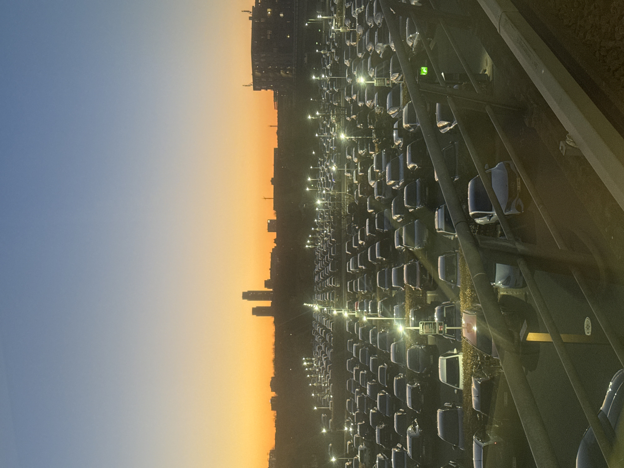 Automated train passes Copenhagen car lot during twilight hours