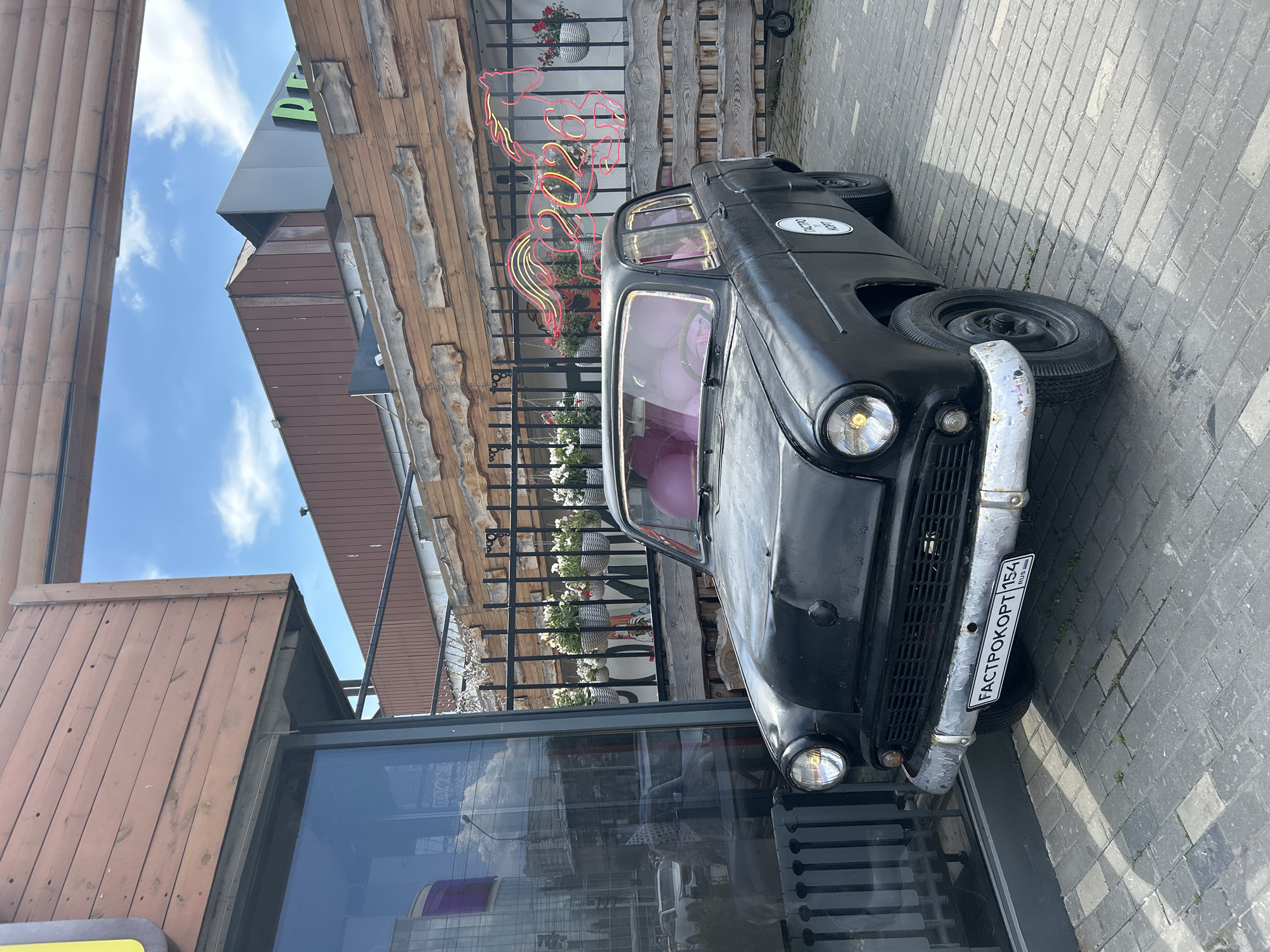Black vintage car with chrome bumper parked on cobblestone sidewalk