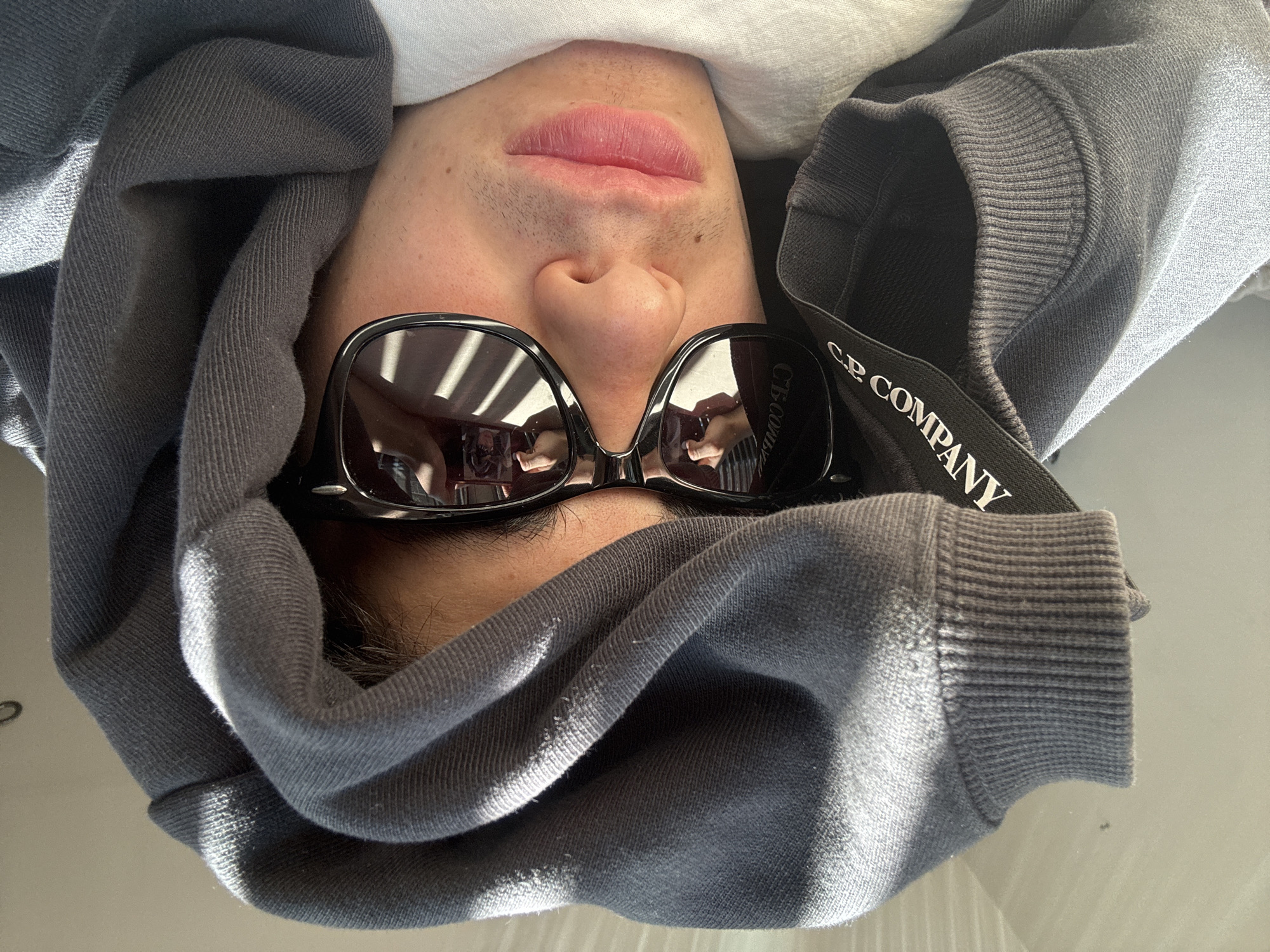 Person in sunglasses lies indoors in London