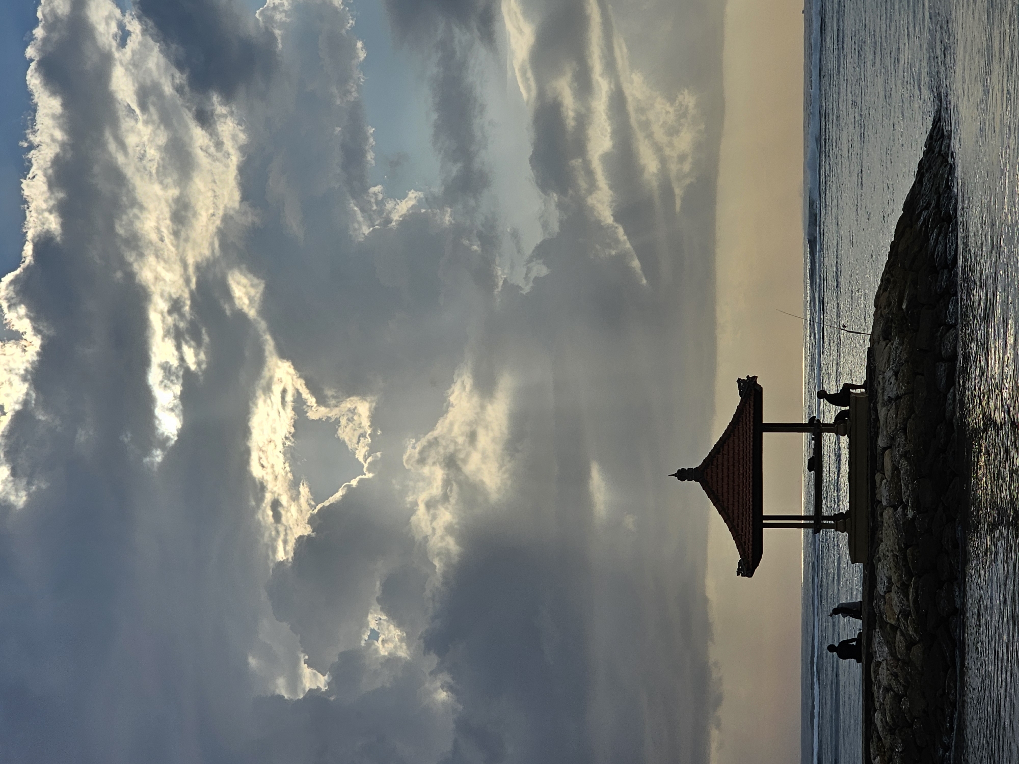 Dusk gathering on Sanur Beach's rocky coastal embankment
