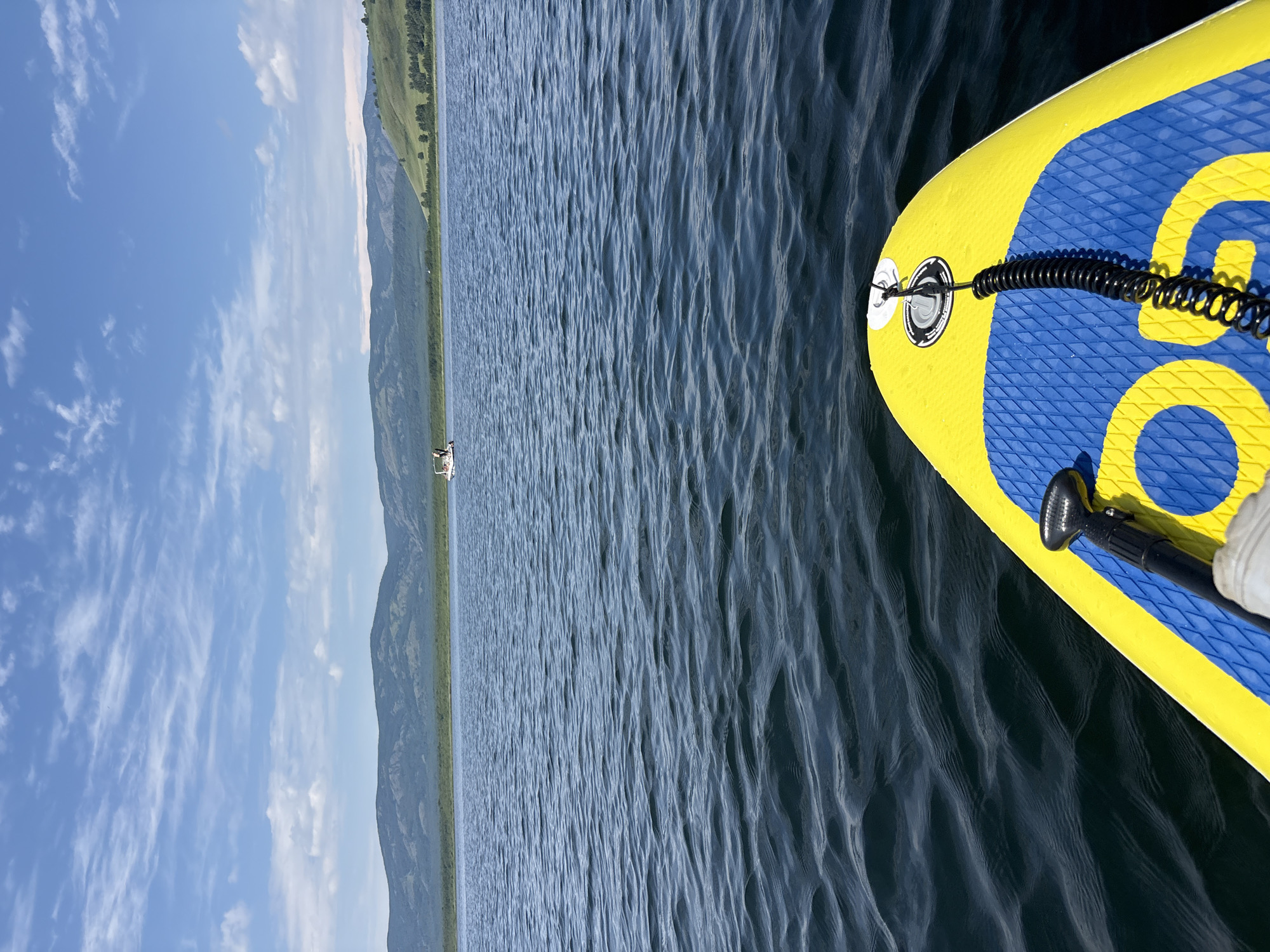 Paddleboarding on a calm Russian lake, white boat in the distance