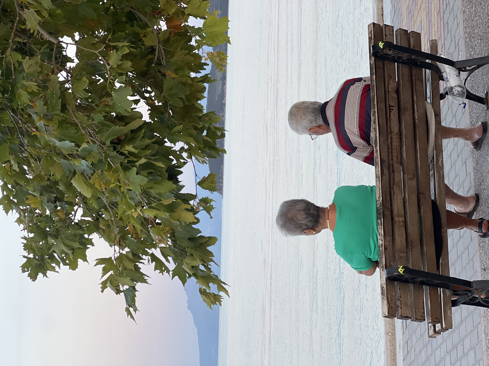 Waterfront bench and a vivid sunset sky over mountain-backed water