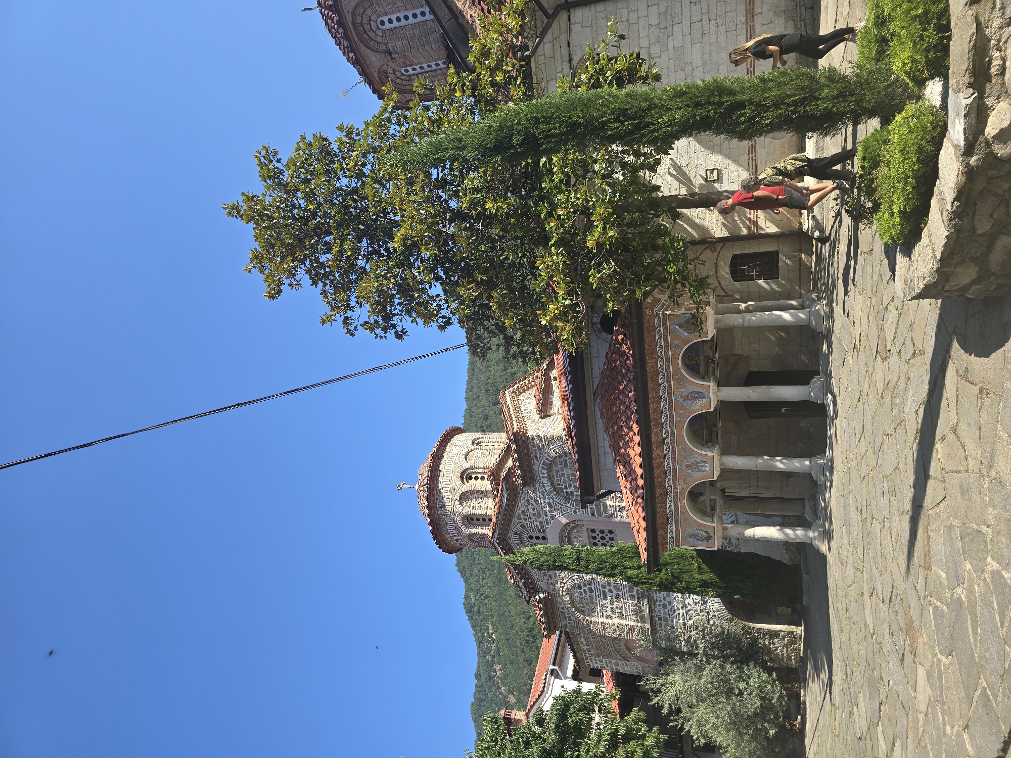 Stone church with domed cross in a sunlit courtyard