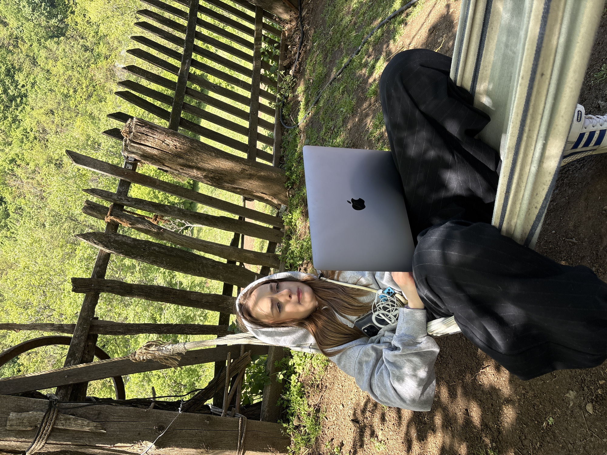 Woman works on laptop while relaxing in hammock outdoors