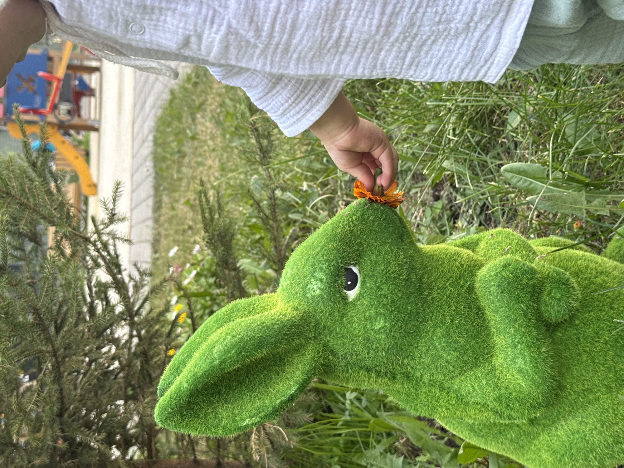 Child plays with green topiary rabbit in Moscow park