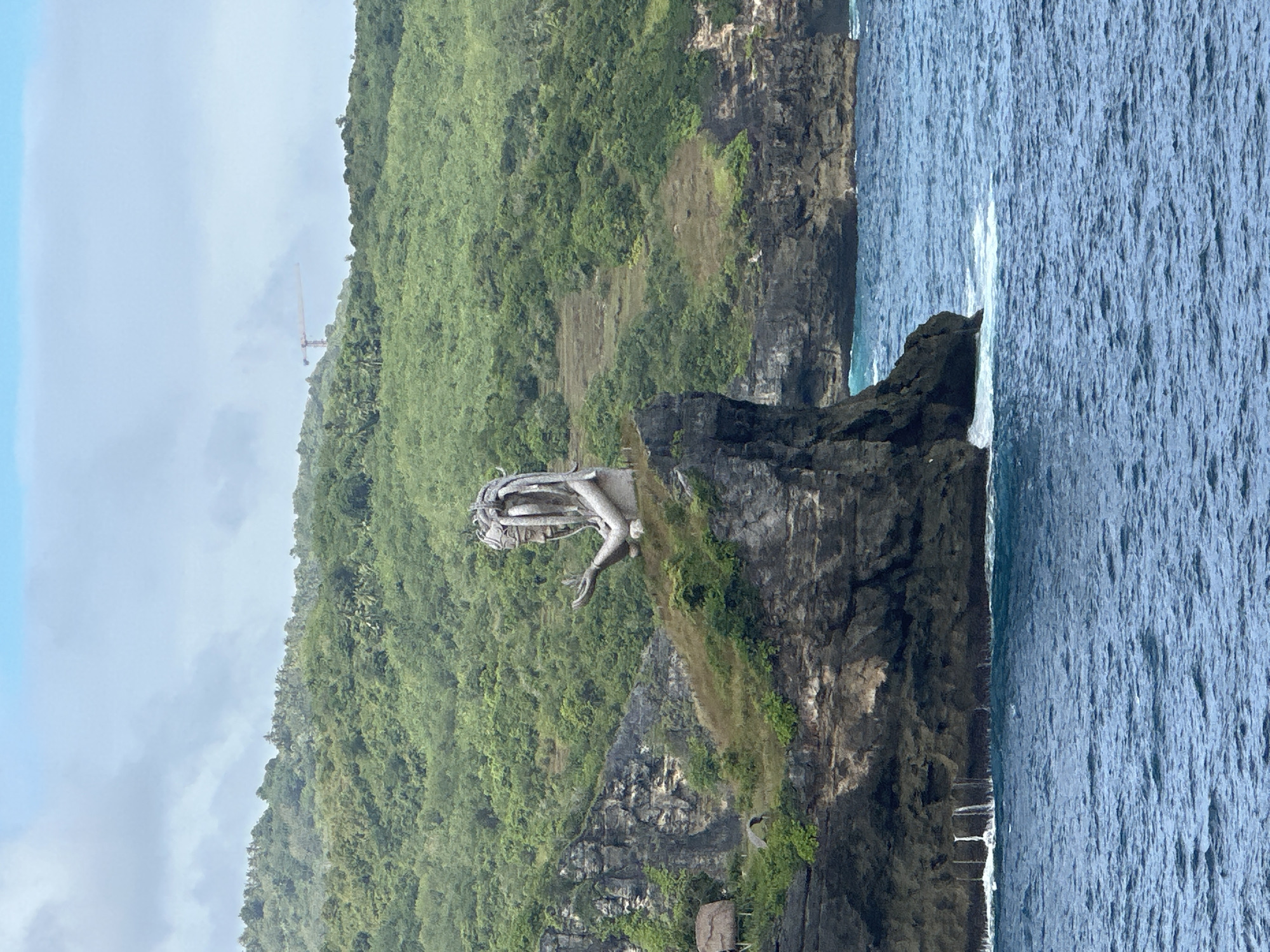 Stone woman statue observed on Nusa Penida cliff overlooking ocean
