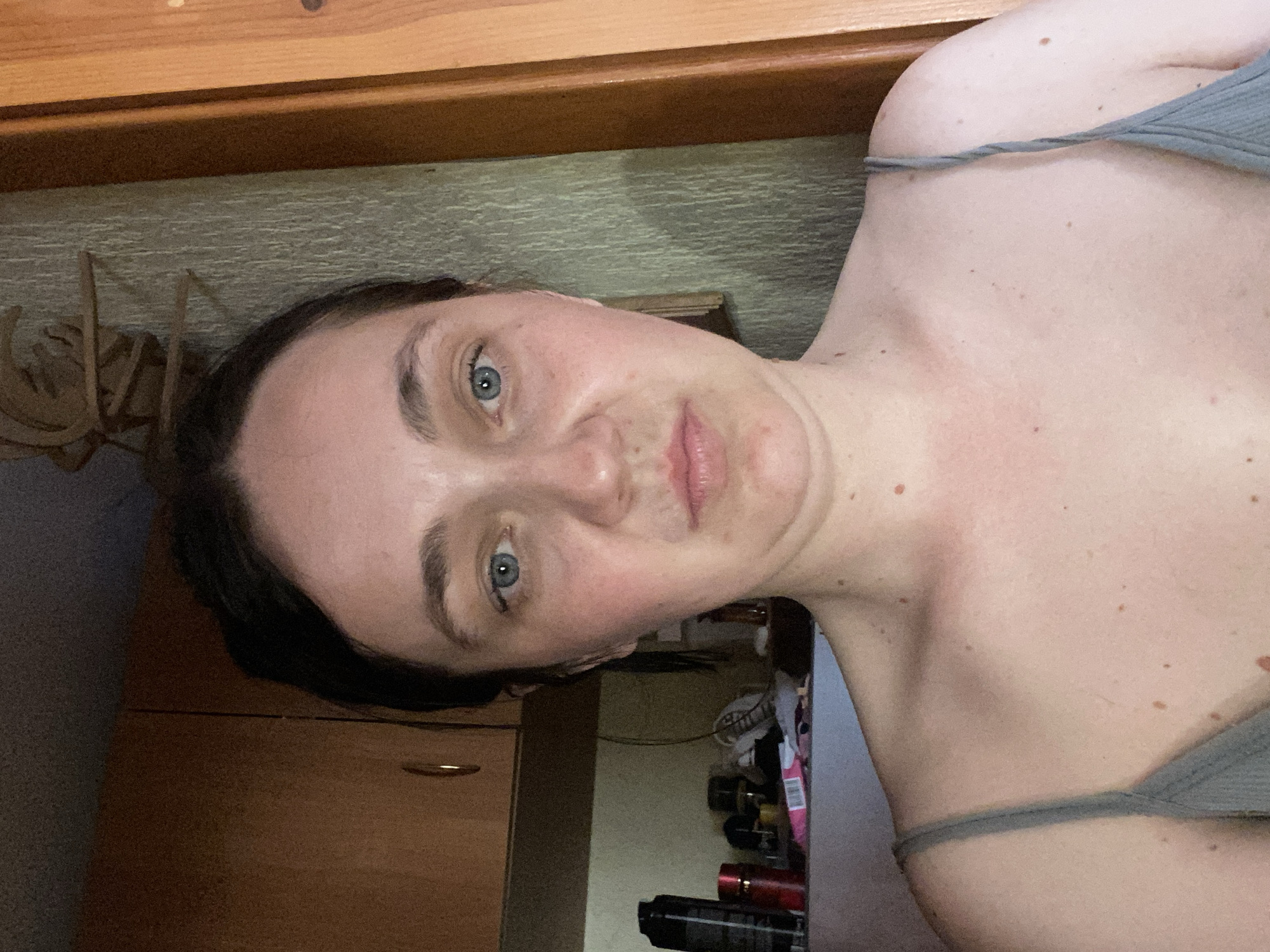Close-up portrait shot, neutral expression, hair pulled back