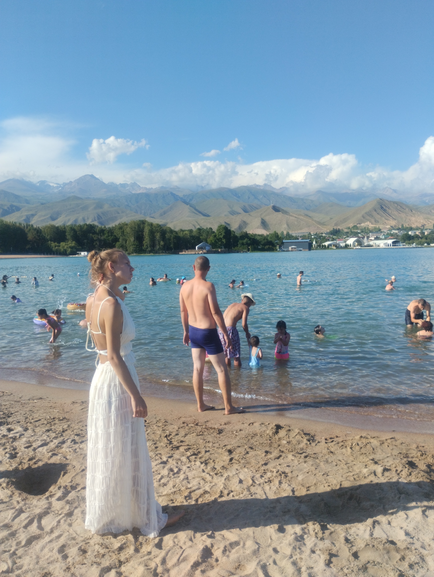 Summer day at Lake Issyk-Kul: swimmers, a camel, and parasailing