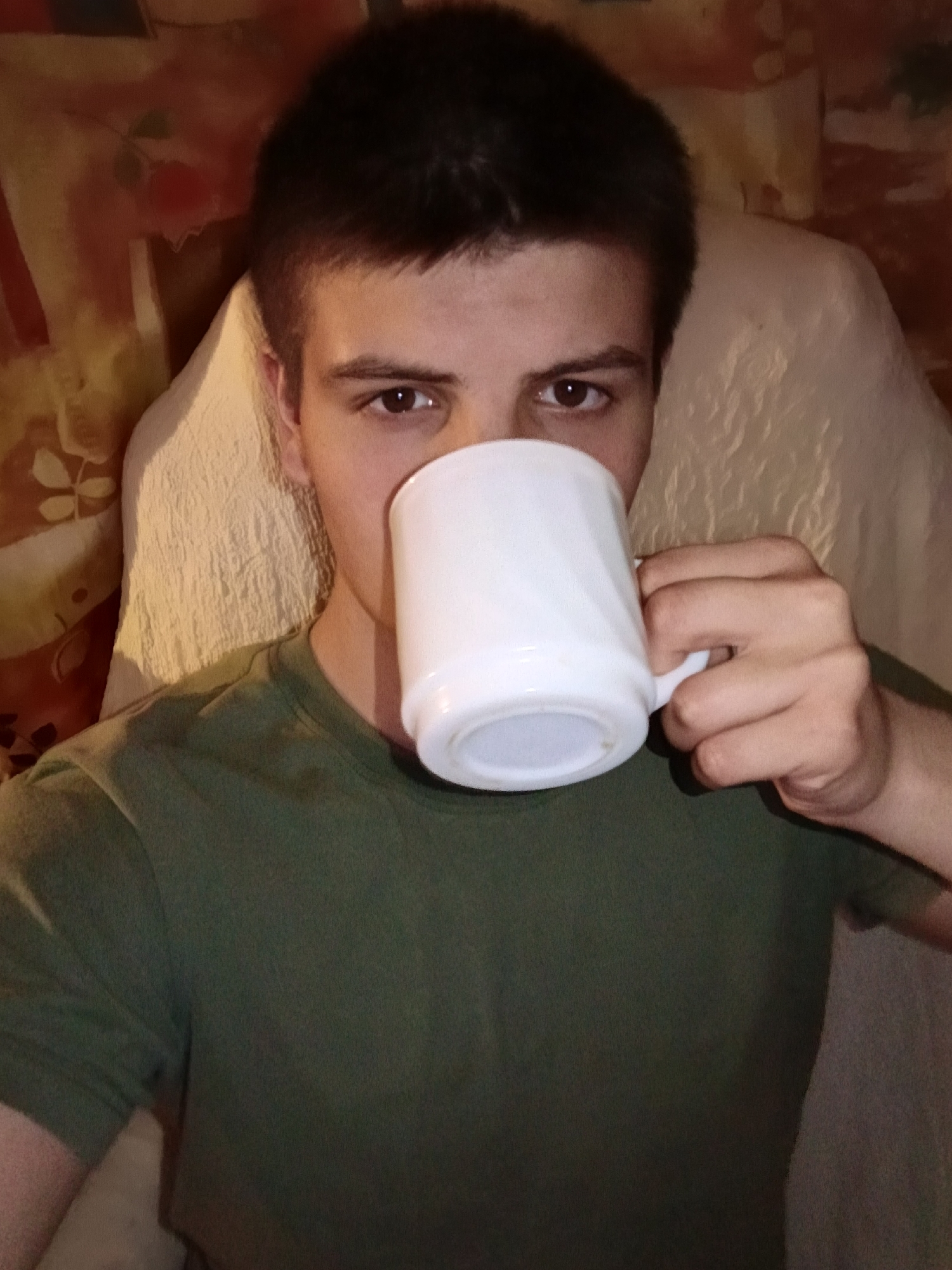 Young man drinks from mug in Russian home setting