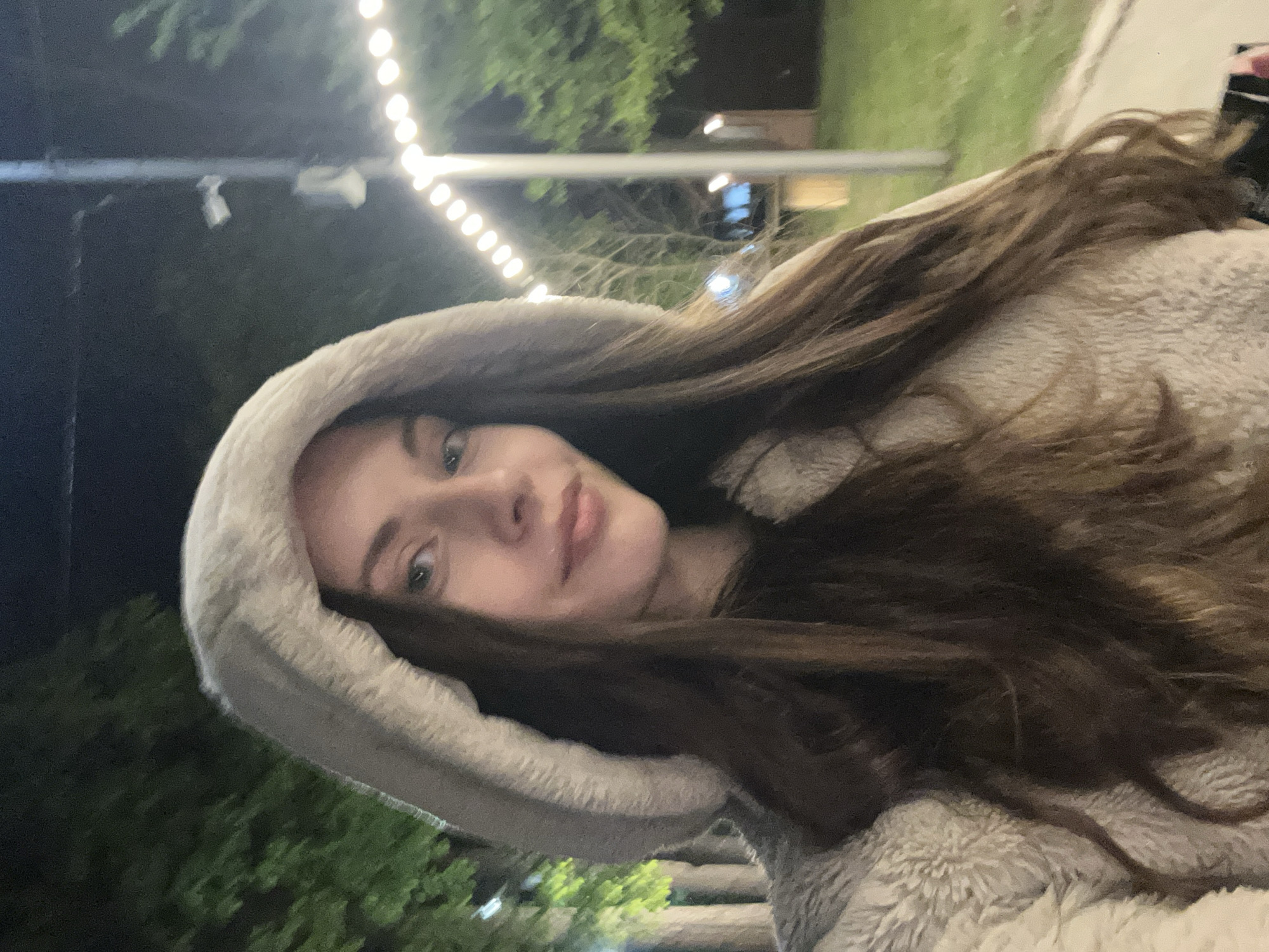 Woman photographed on illuminated nighttime pathway amid string lights
