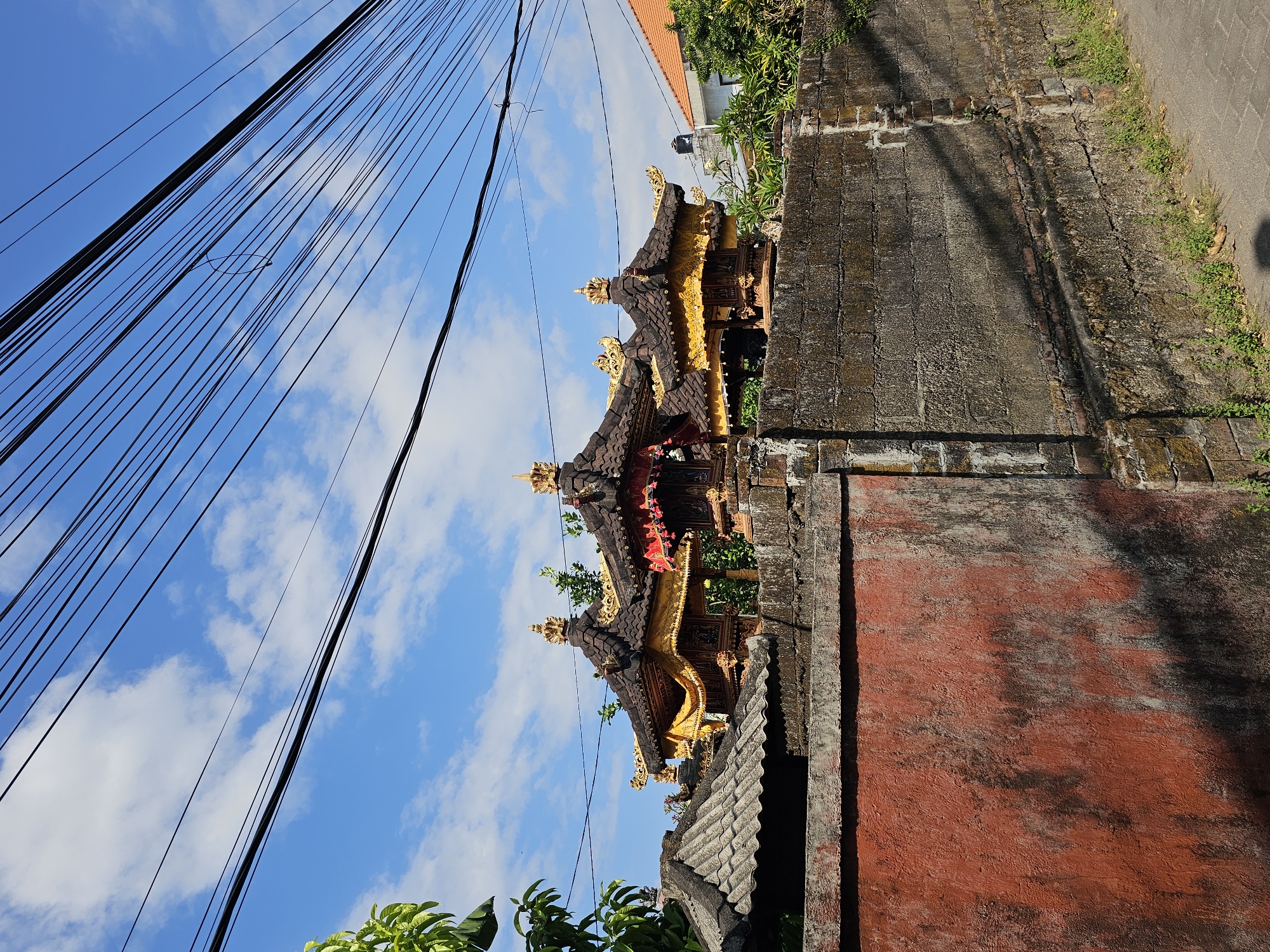 Morning delivery operations near traditional Balinese temple in Denpasar