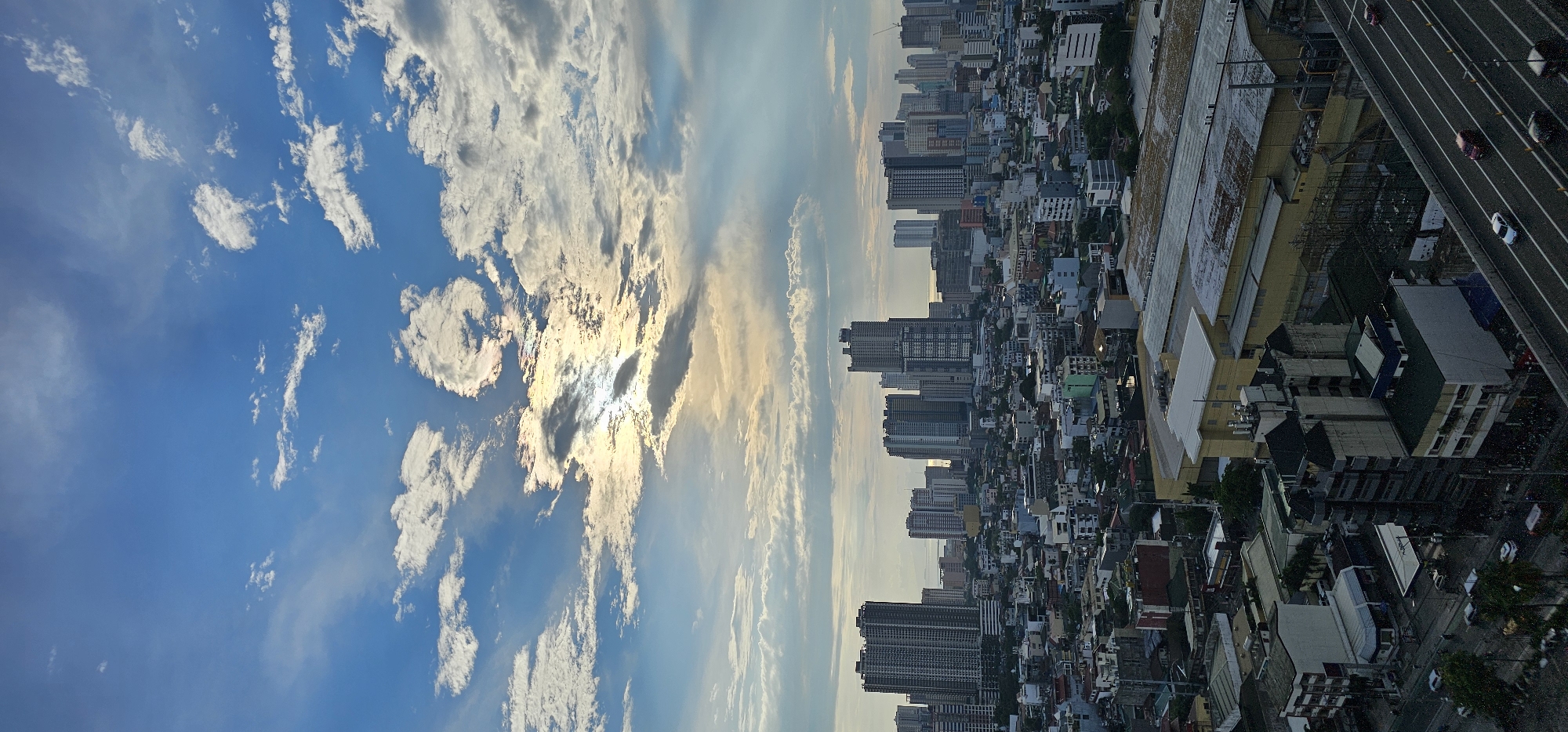 Makati skyline from above, city sprawl under cumulus clouds