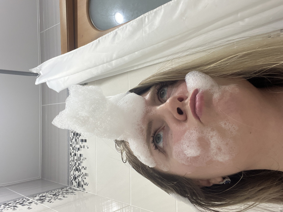 Woman performs skincare routine while cat watches in Chaikovsky