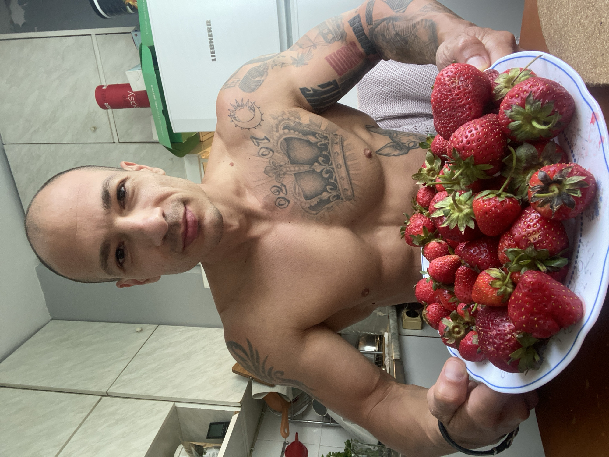 Tattooed man holds strawberries in Pleven kitchen