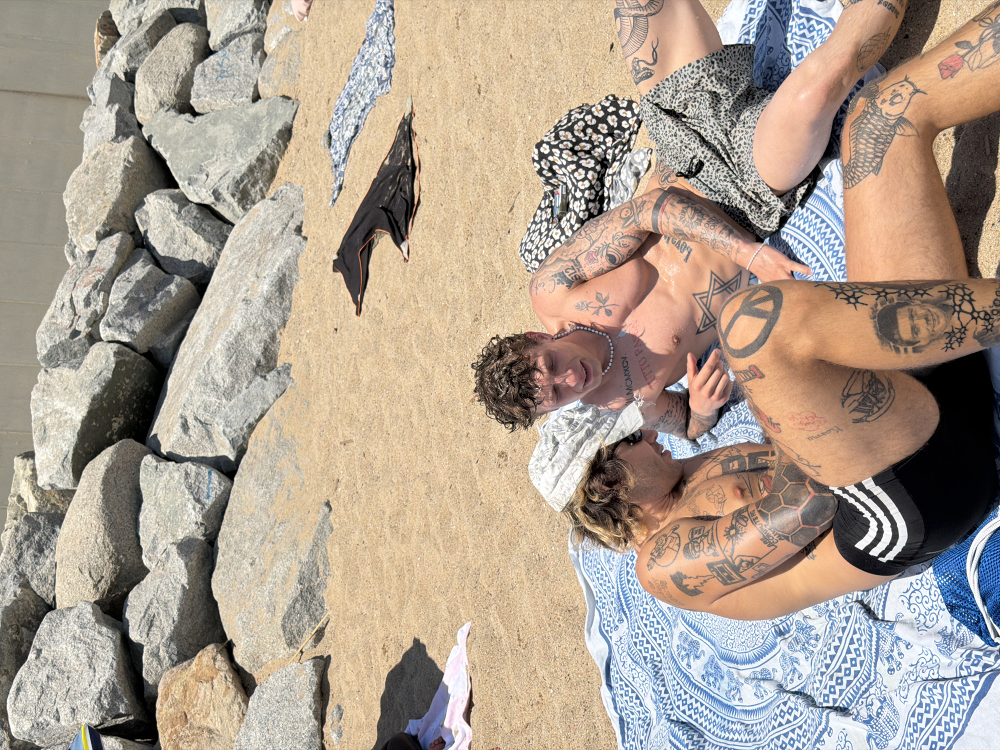 Tattooed beachgoers swimming and relaxing on Barcelona's coast