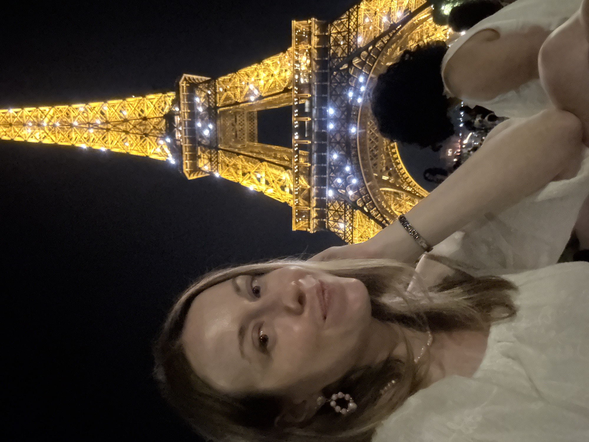 Eiffel Tower lit up at night, crowds gathered below