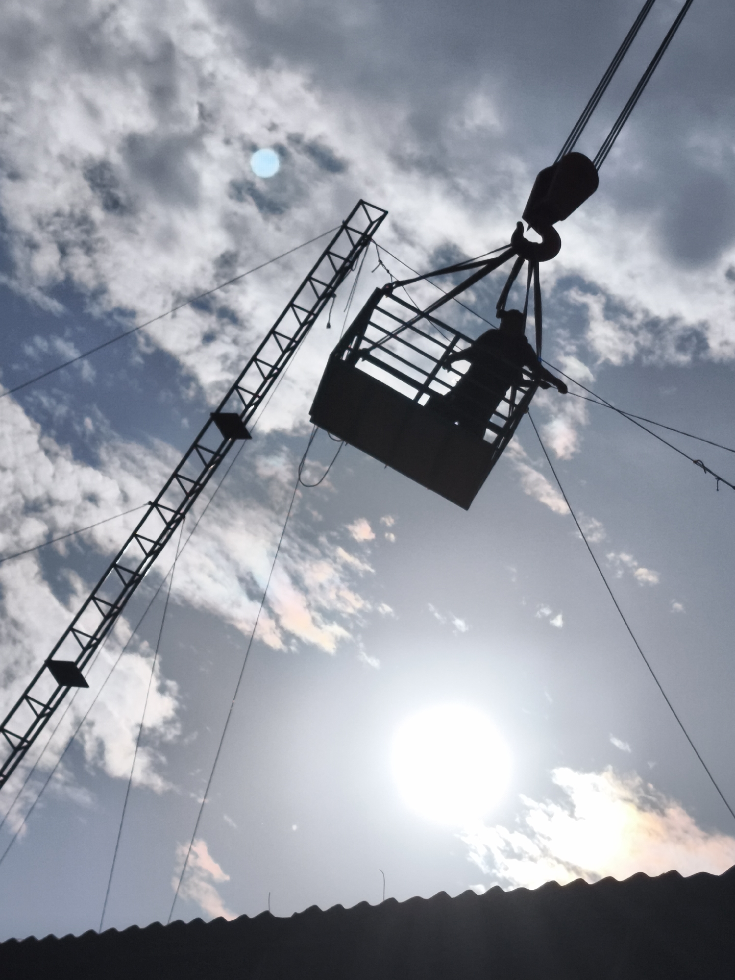Crane lifts two people in basket above Chimbote rooftops