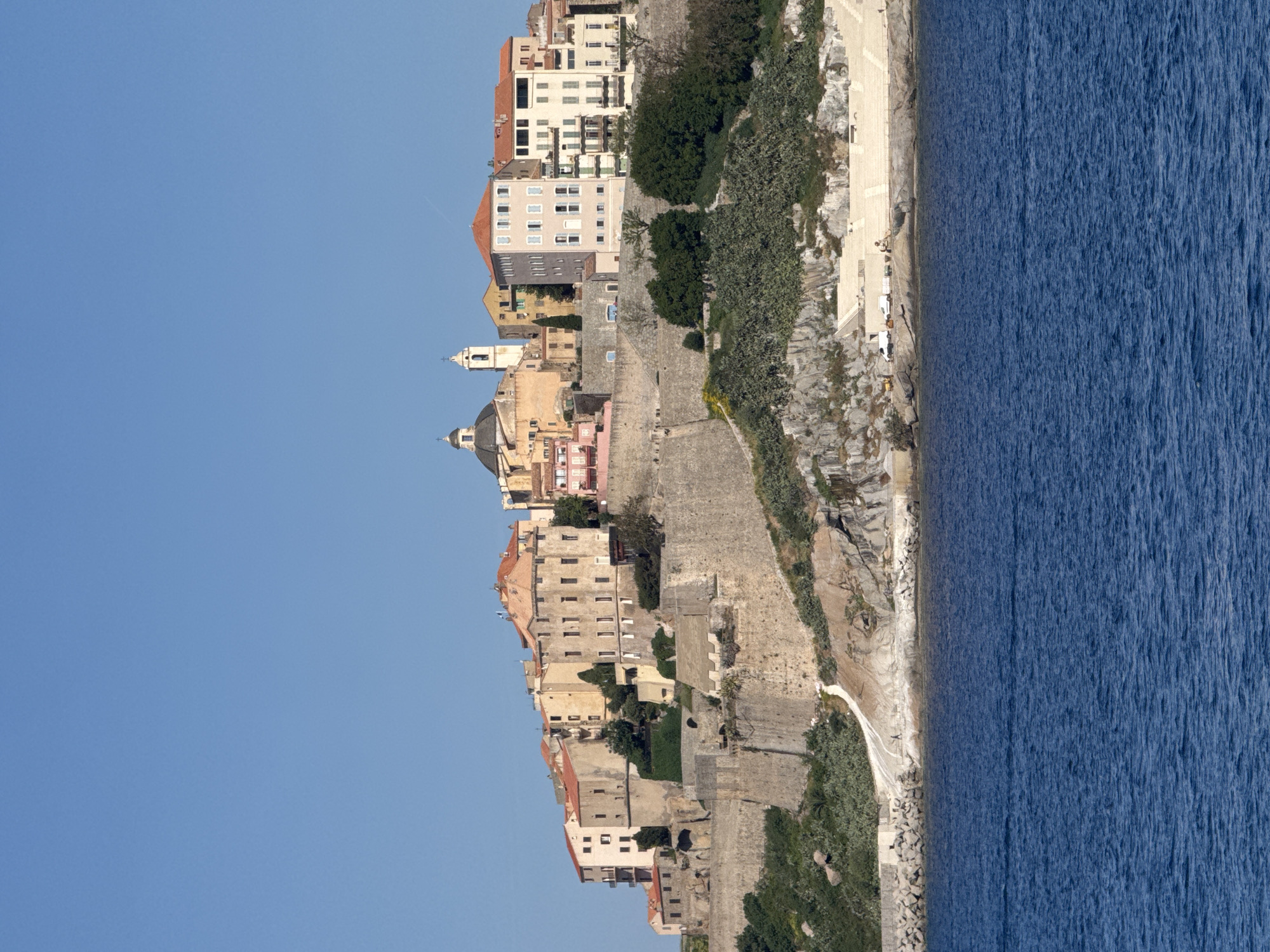 Coastal cliff town observed under clear morning skies