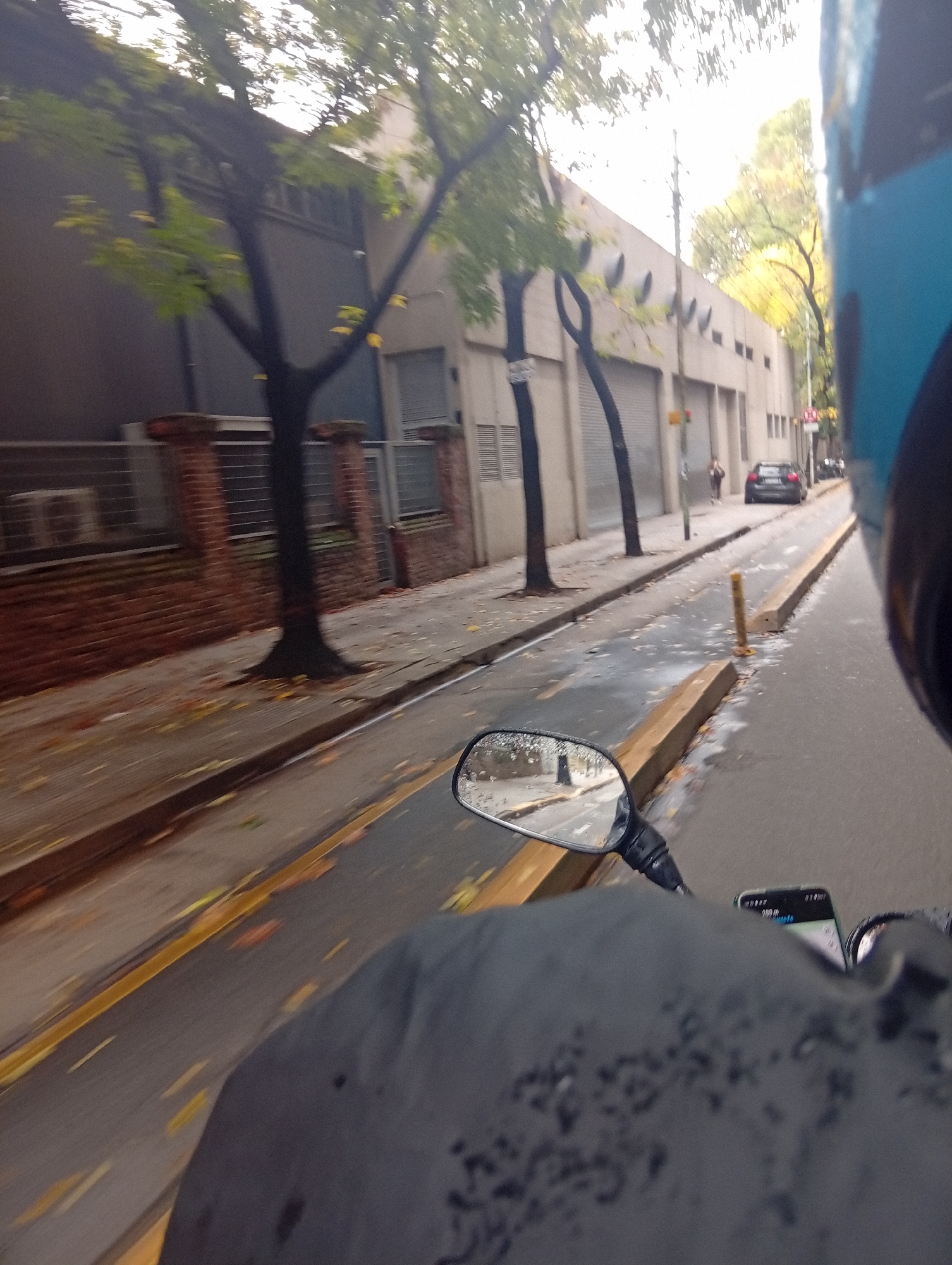 Motorcyclist rides through wet Buenos Aires streets during overcast afternoon