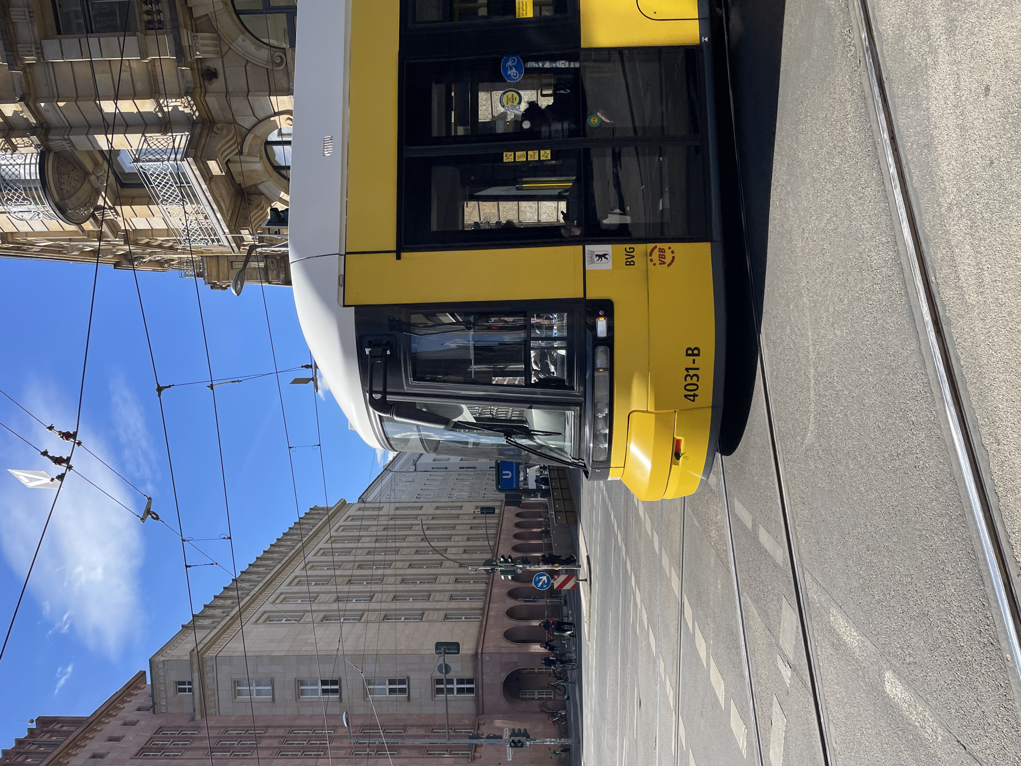 Berlin tram operates under sunny skies amid pedestrian traffic