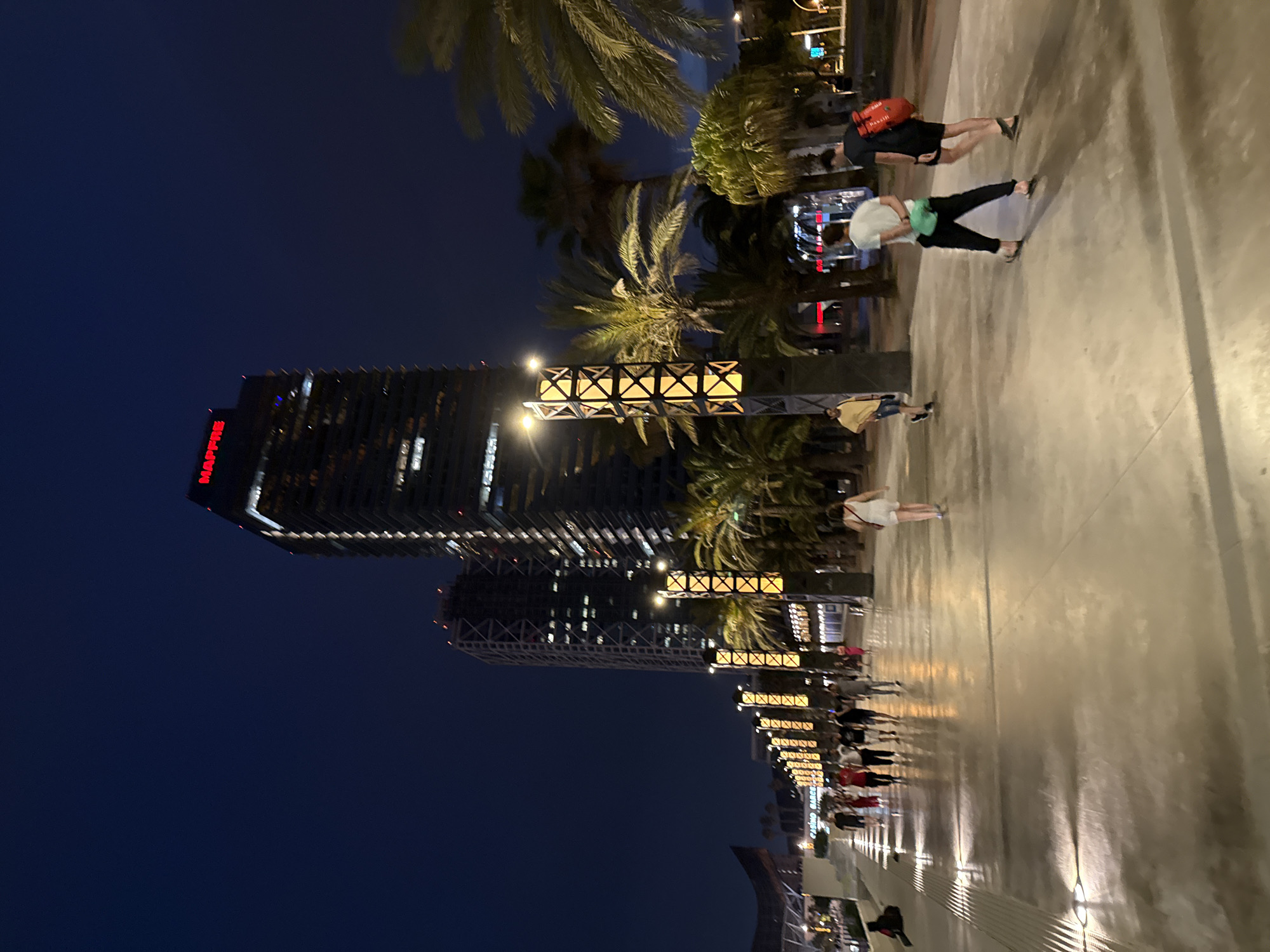 Evening crowds stroll Barcelona's lit beachfront promenade
