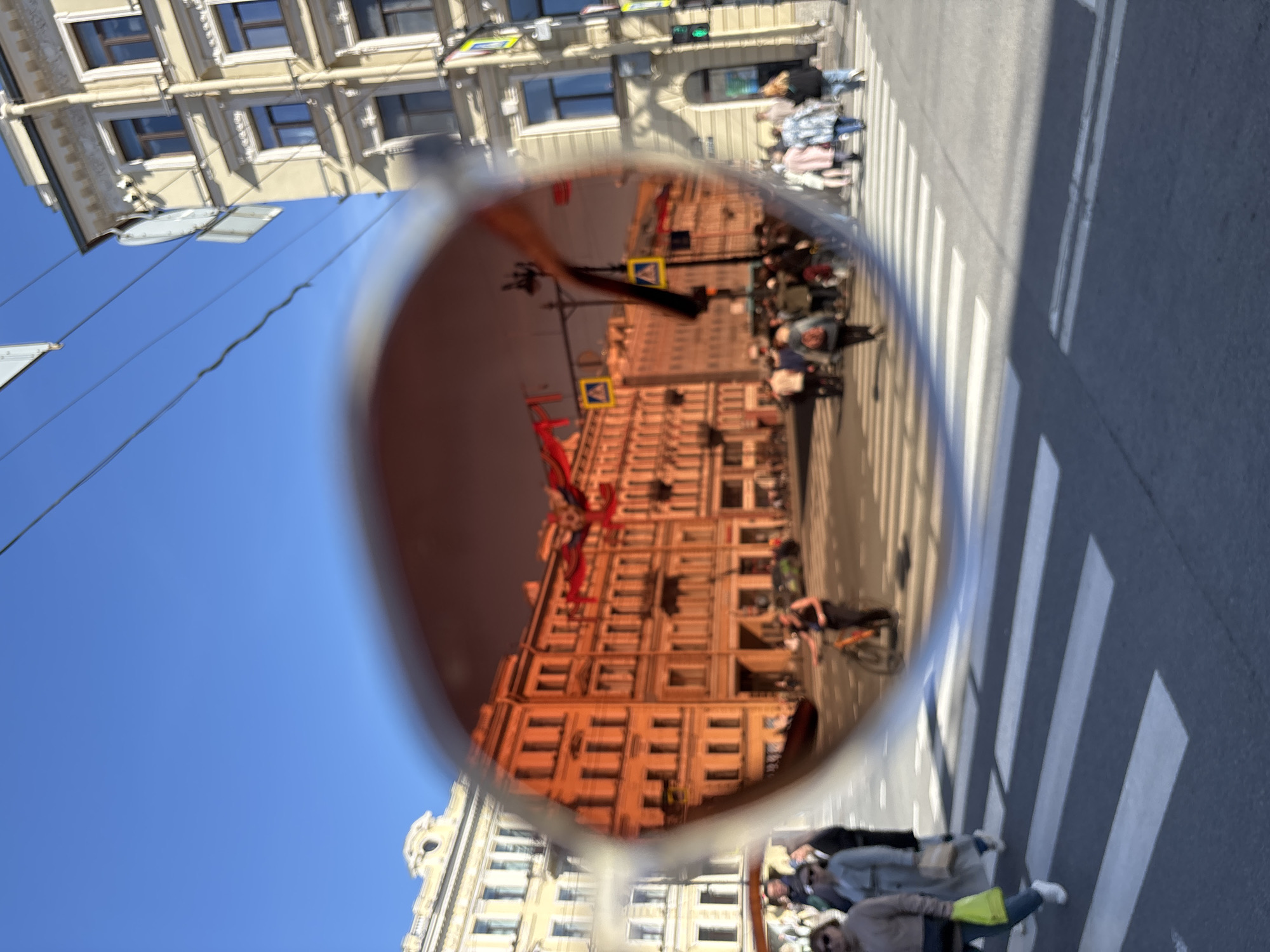 Sunglasses reflection captures Saint Petersburg street scene with red banners