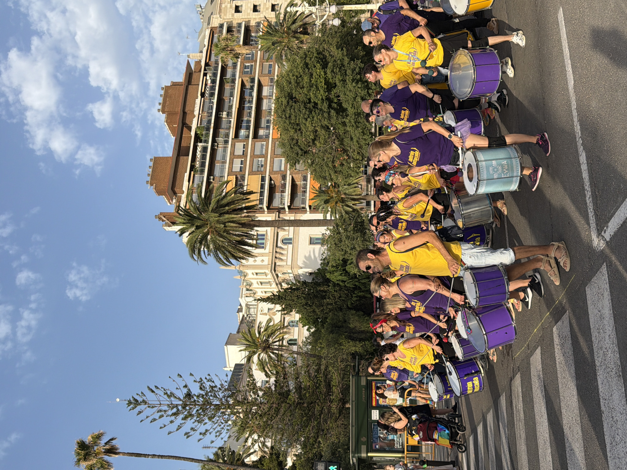 Pride parade crosses city bridge with flags, drums, and festive crowds