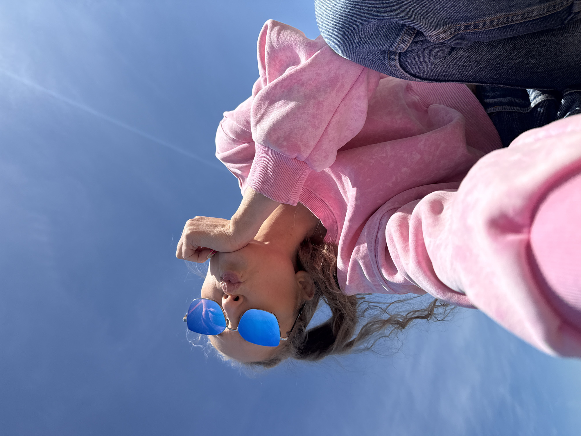 Person in pink hoodie photographed against blue sky in Chaykovsky
